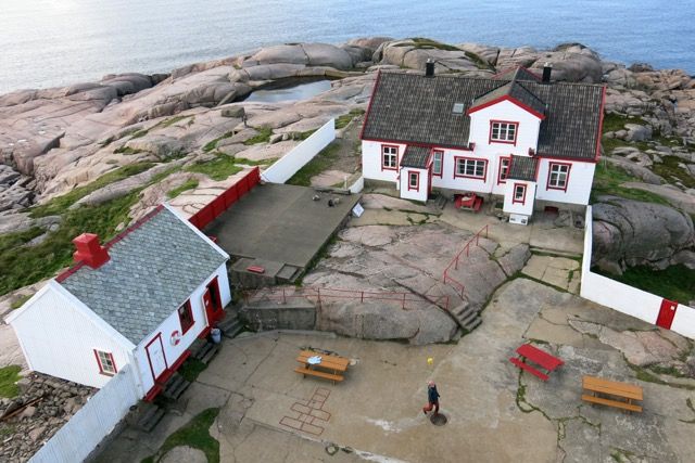 Oversiktsbilde over huset på Ryvingen fyr. Huset er hvitt med røde detaljer (røde lister) og svart tak.