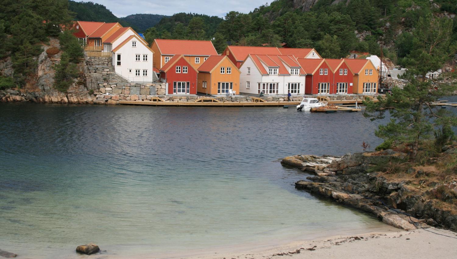 Modern holiday homes in different colors by the sea, with a beach in the foreground.