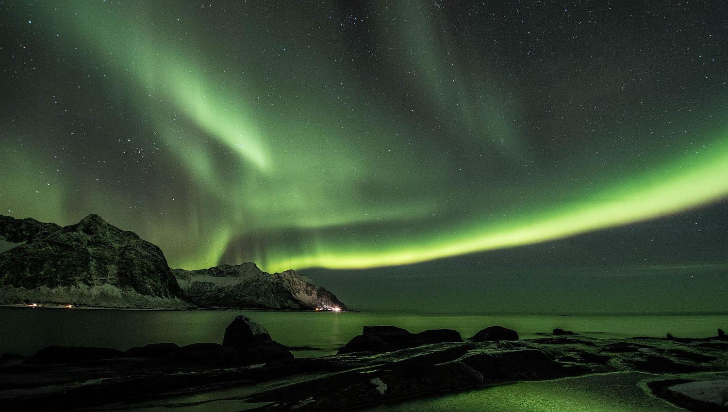 Northern Lights above the sea and mountains on Senja.