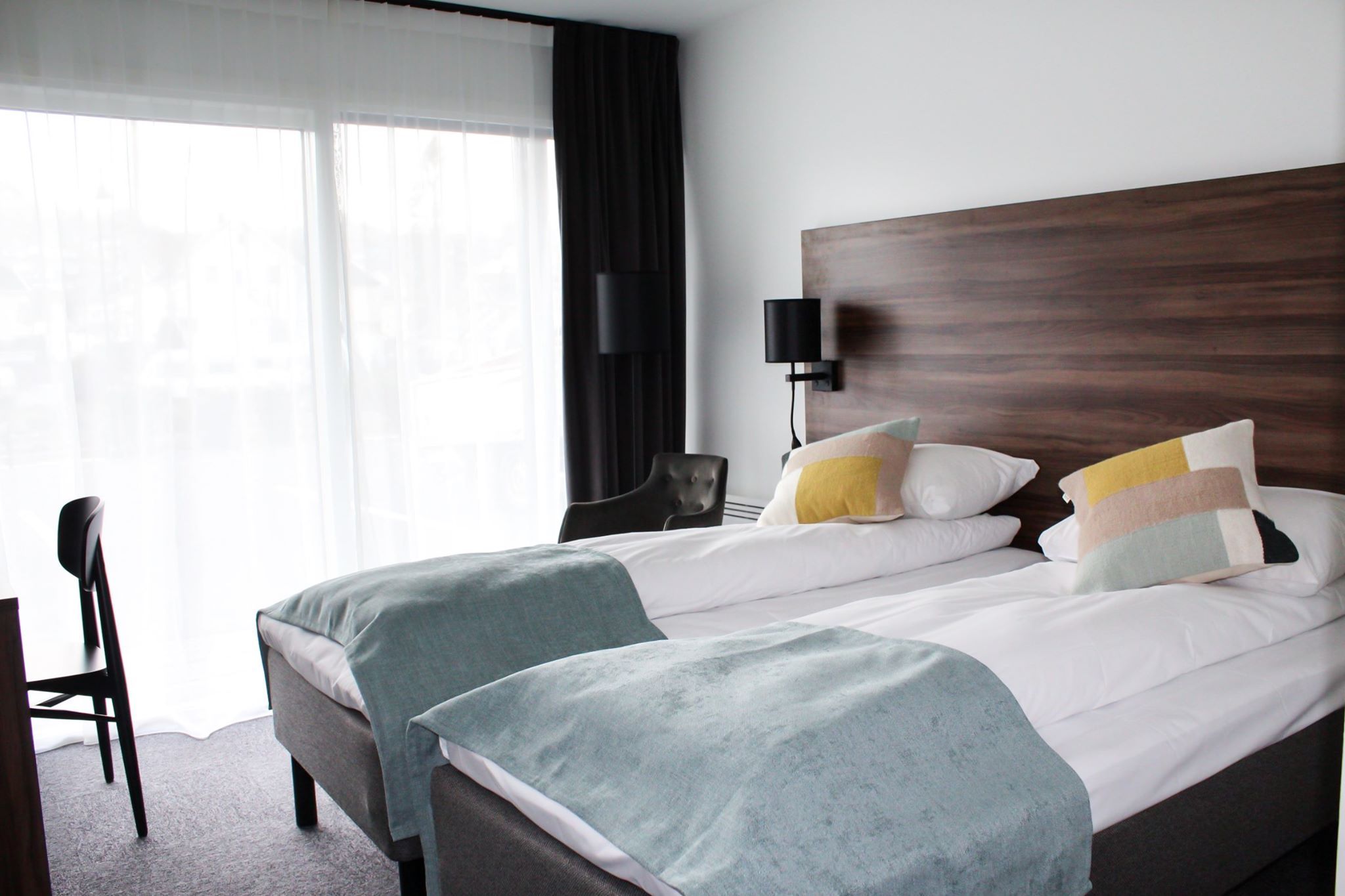 Bright hotel room with two single beds and a fjord view from the balcony.