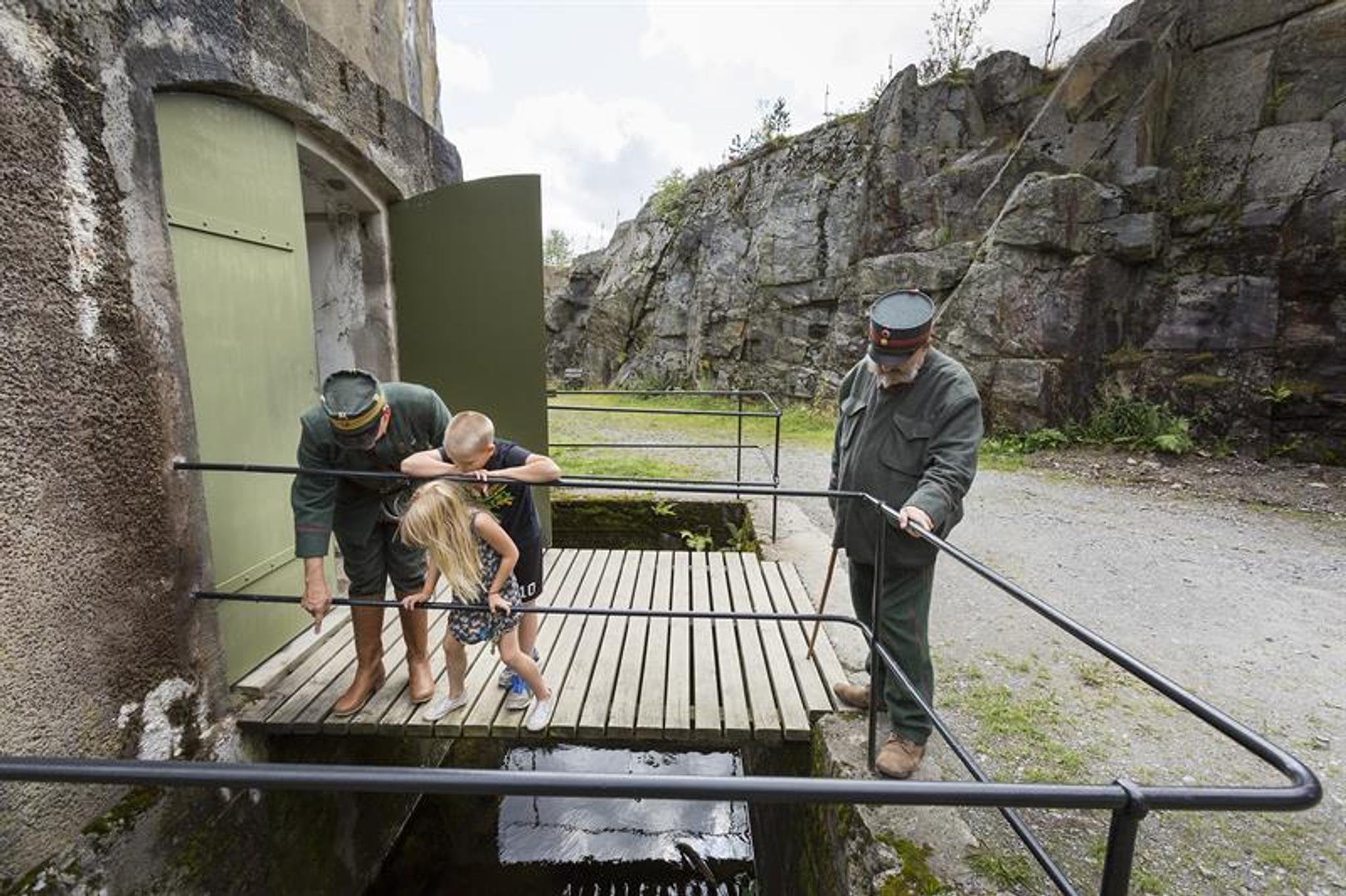 two men in military uniforms and two kids looking down at something at a fortress