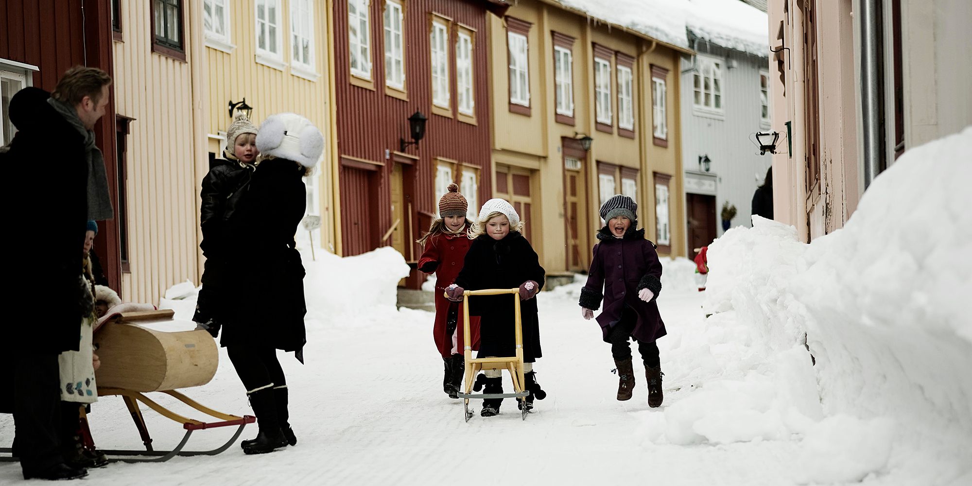 De meisjes gebruiken stepsleeën om in de winter door de straten van Røros te rijden in Trøndelag