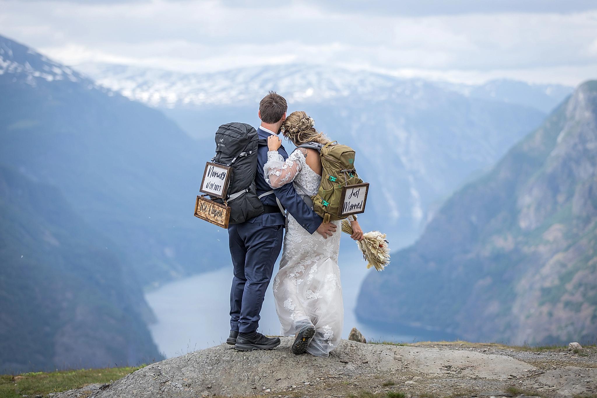 Two newly-weds who just hiked to a mountain enjoying a beautiful fjord view.
