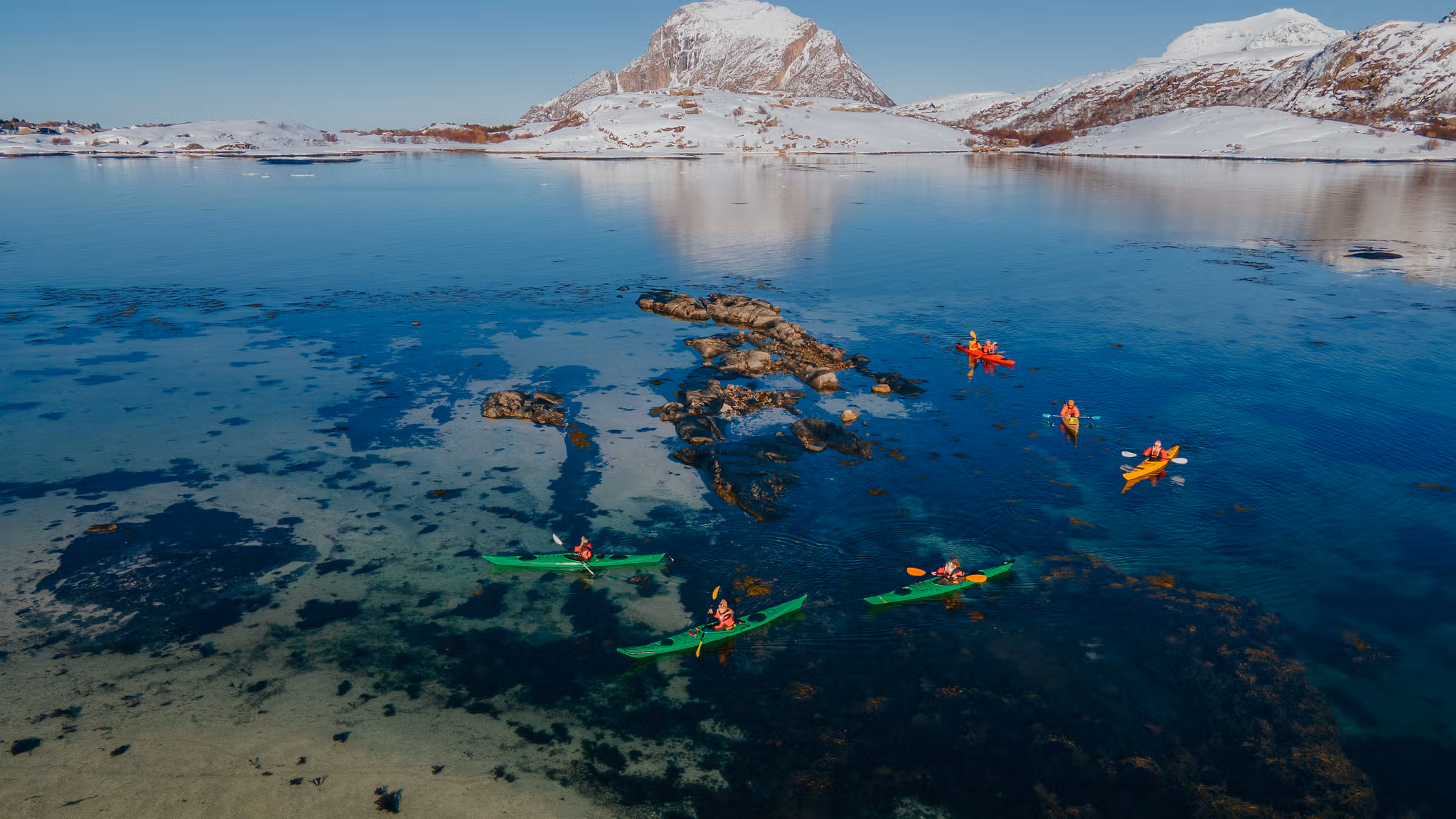 People kayaking in winter landscape.