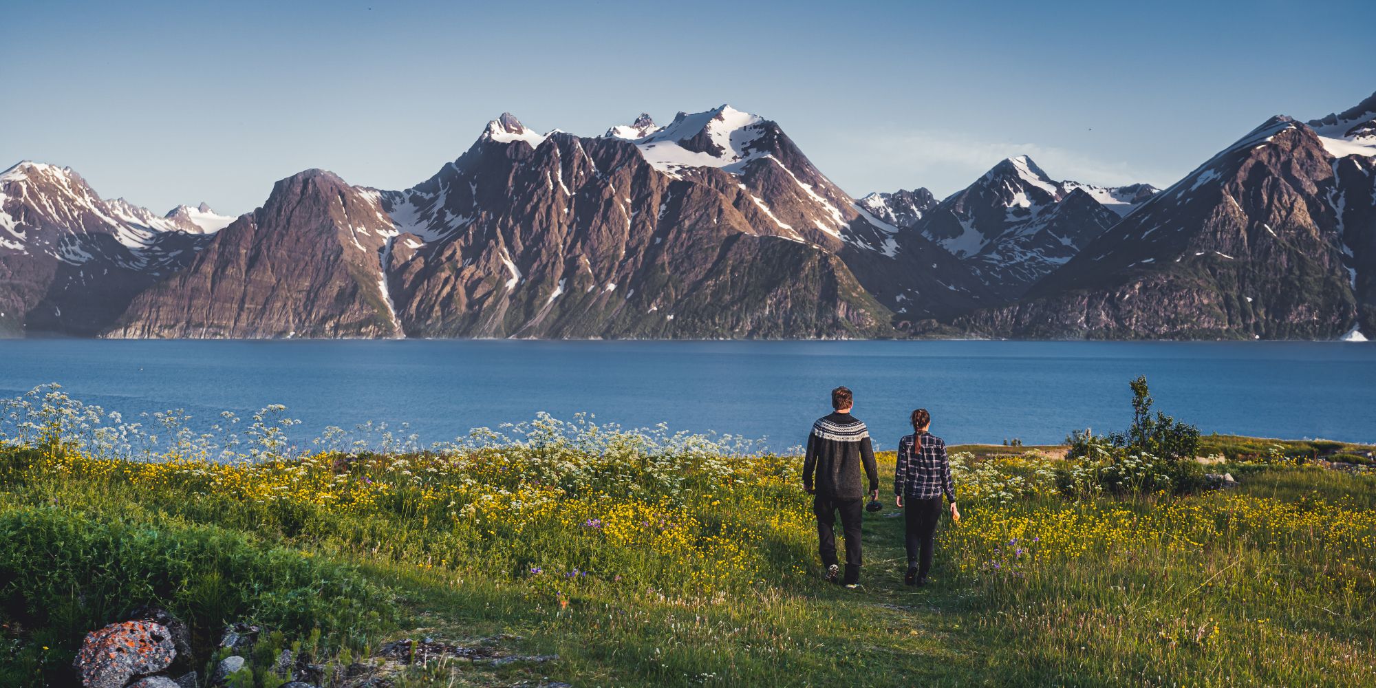 Two people walking hand in hand in the scenic mountain landscape of Lyngenfjord, Northern Norway