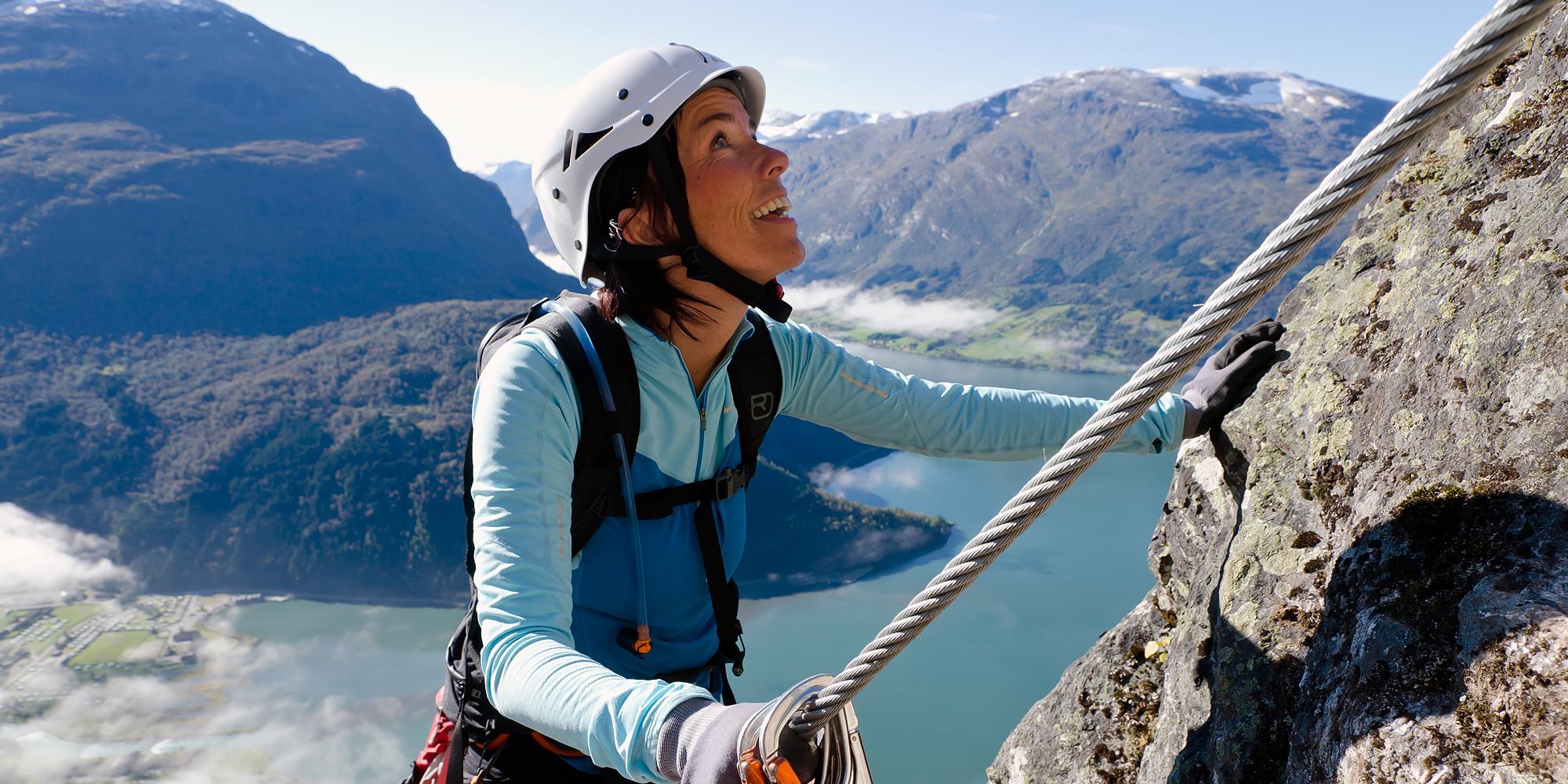 En dame klatrer en fjellvegg i Loen