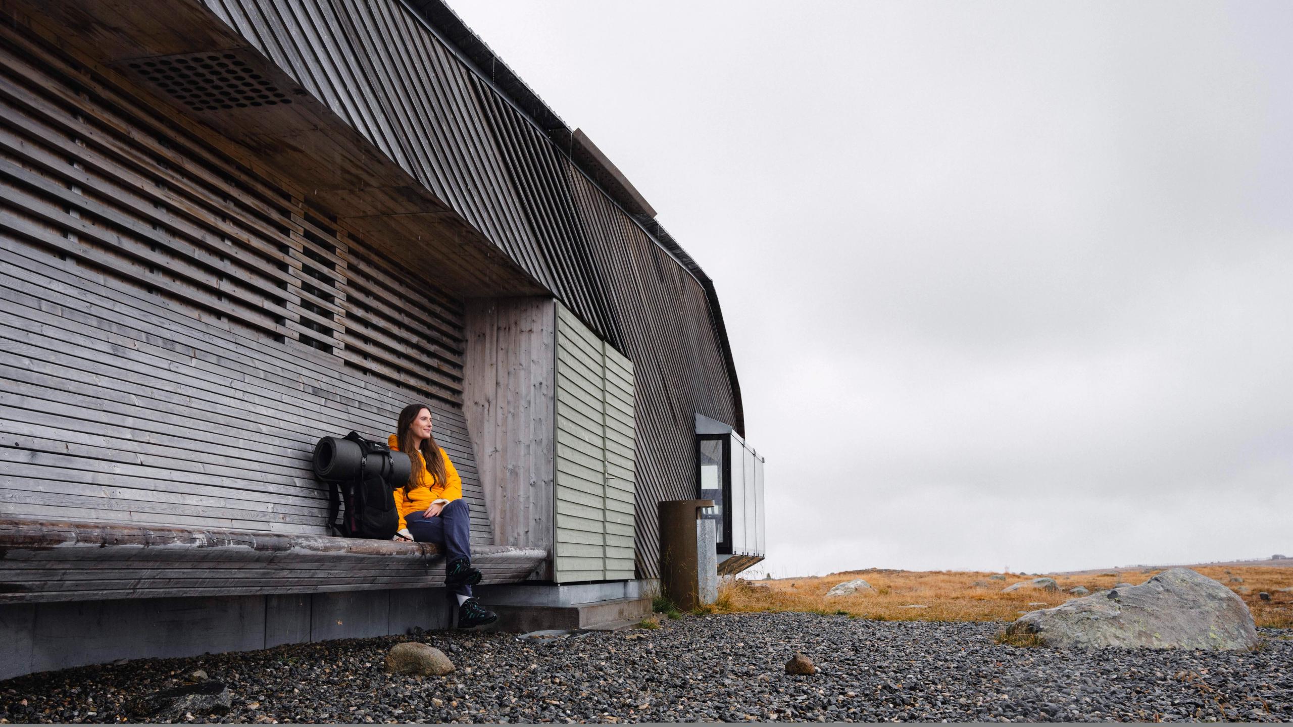 A woman sitting outside of Valdresflye Café in autumn.