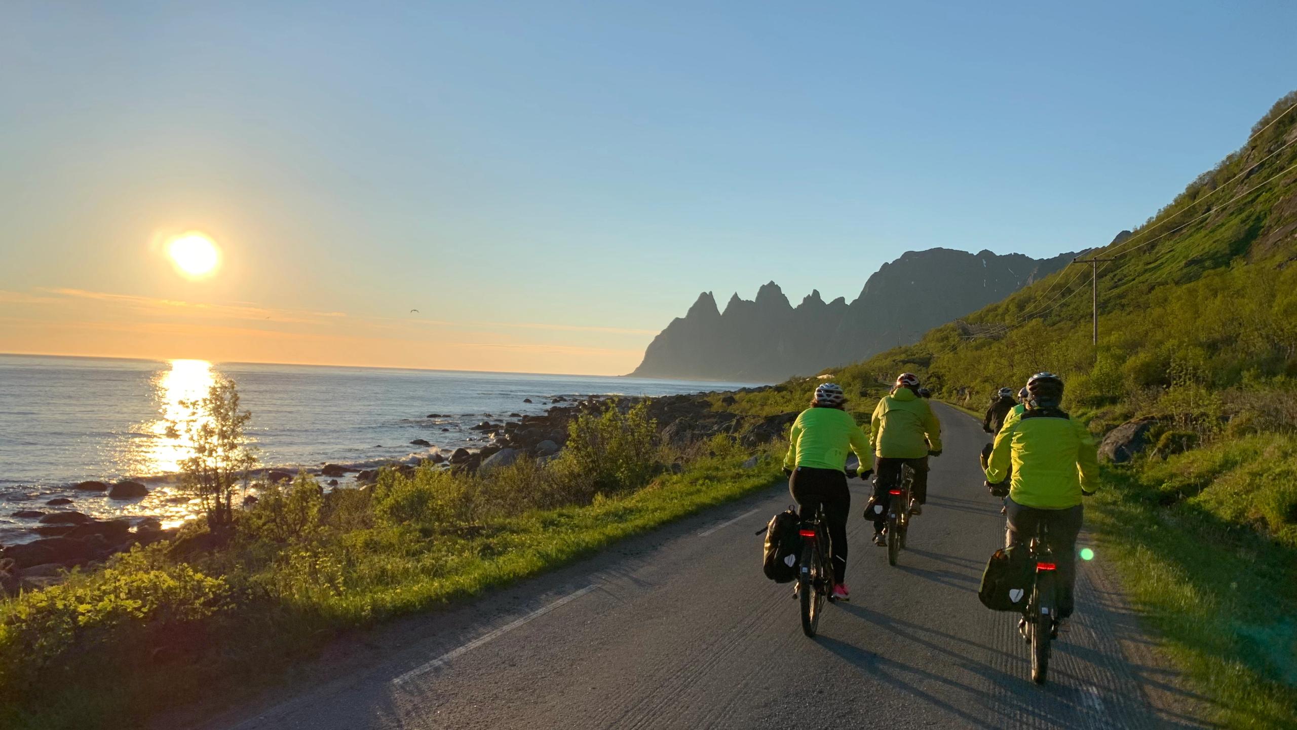Folk på sykkeltur under midnattsolen i Senja