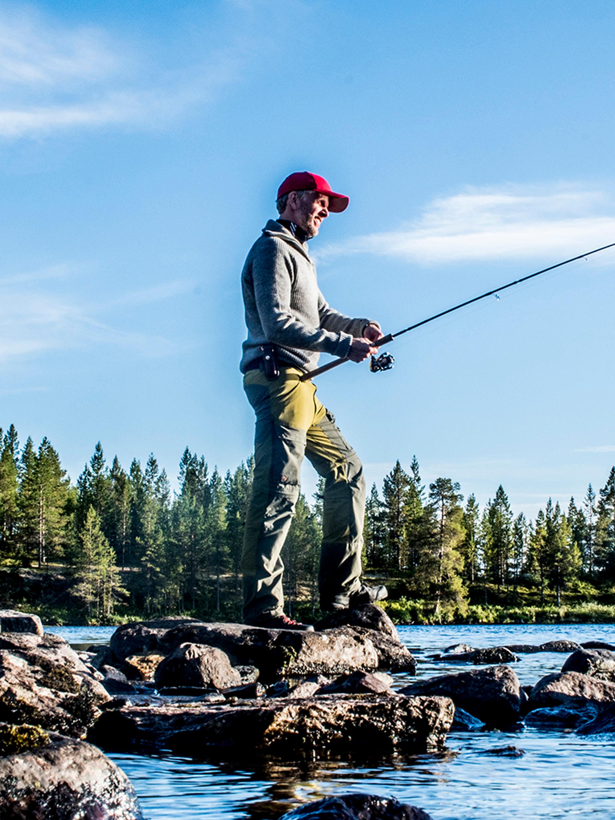 A man freshwater fishing on a sunny day in Femundsmarka National Park in Eastern Norway