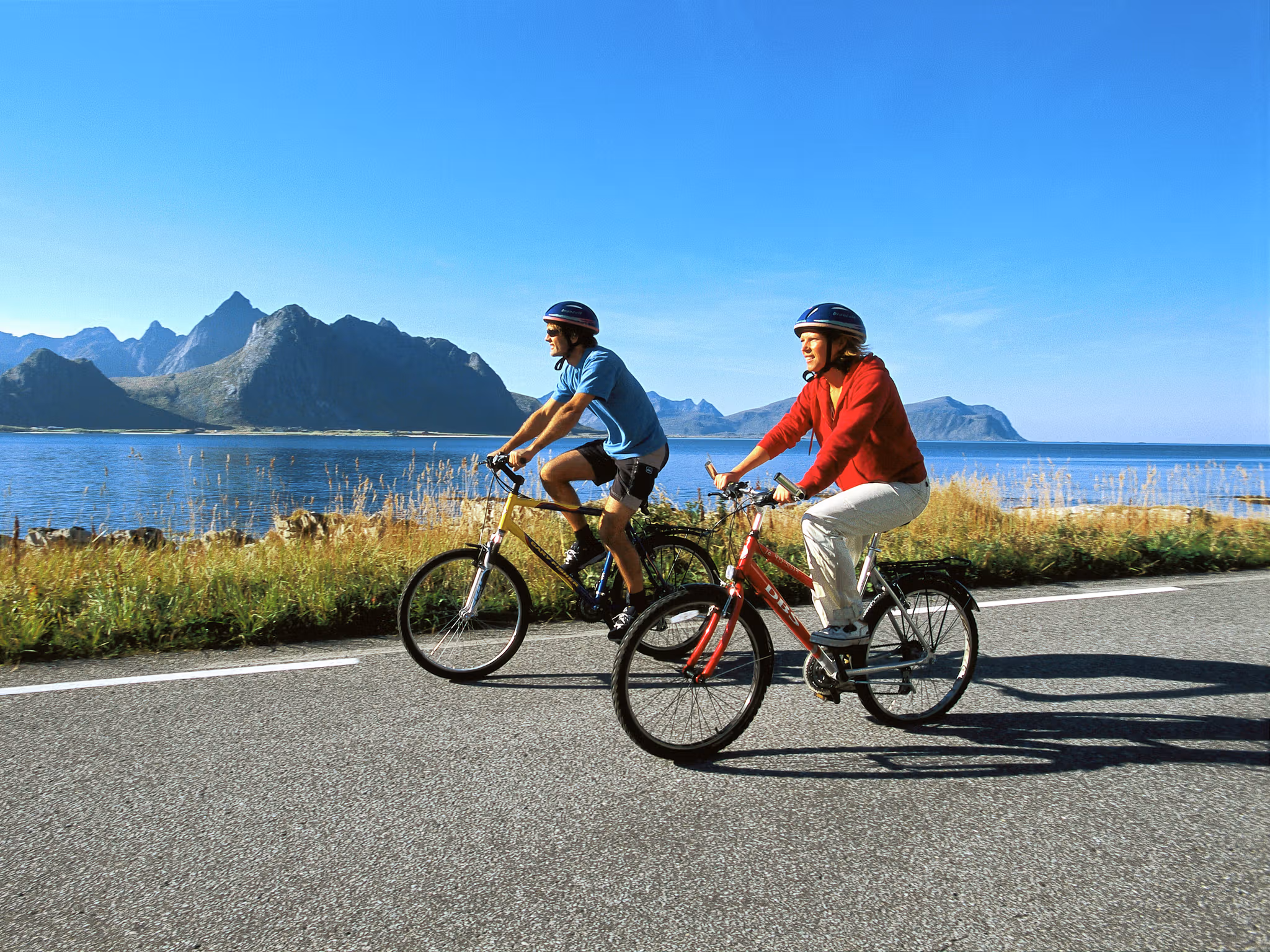 Two people cycling along the coast of Lofoten in Northern Norway