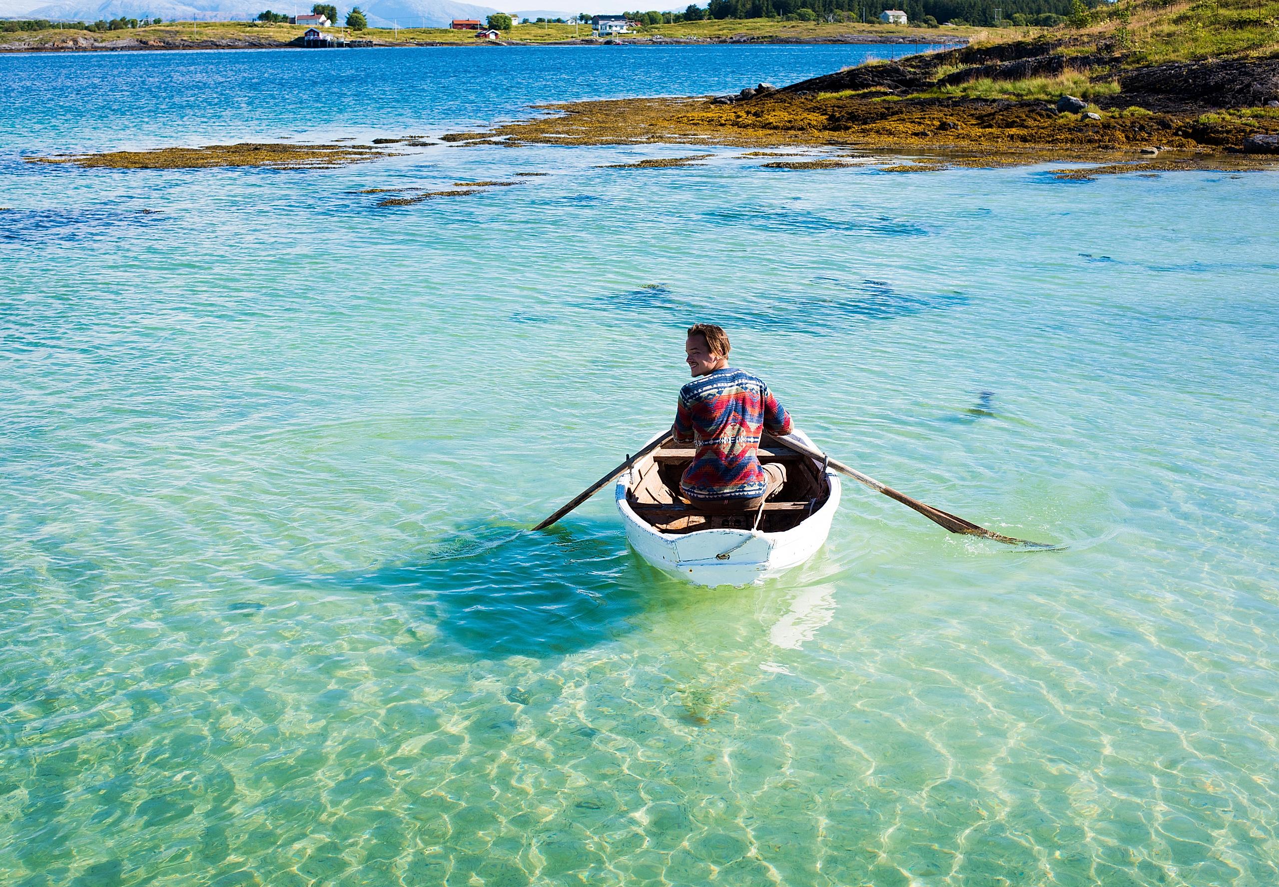 A person in a rowing boat in crystal clear water. Helgeland, Northern Norway.