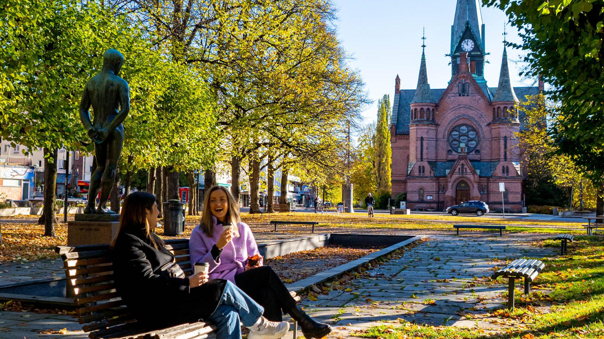 Two women drinking coffee at a bench at Sagene