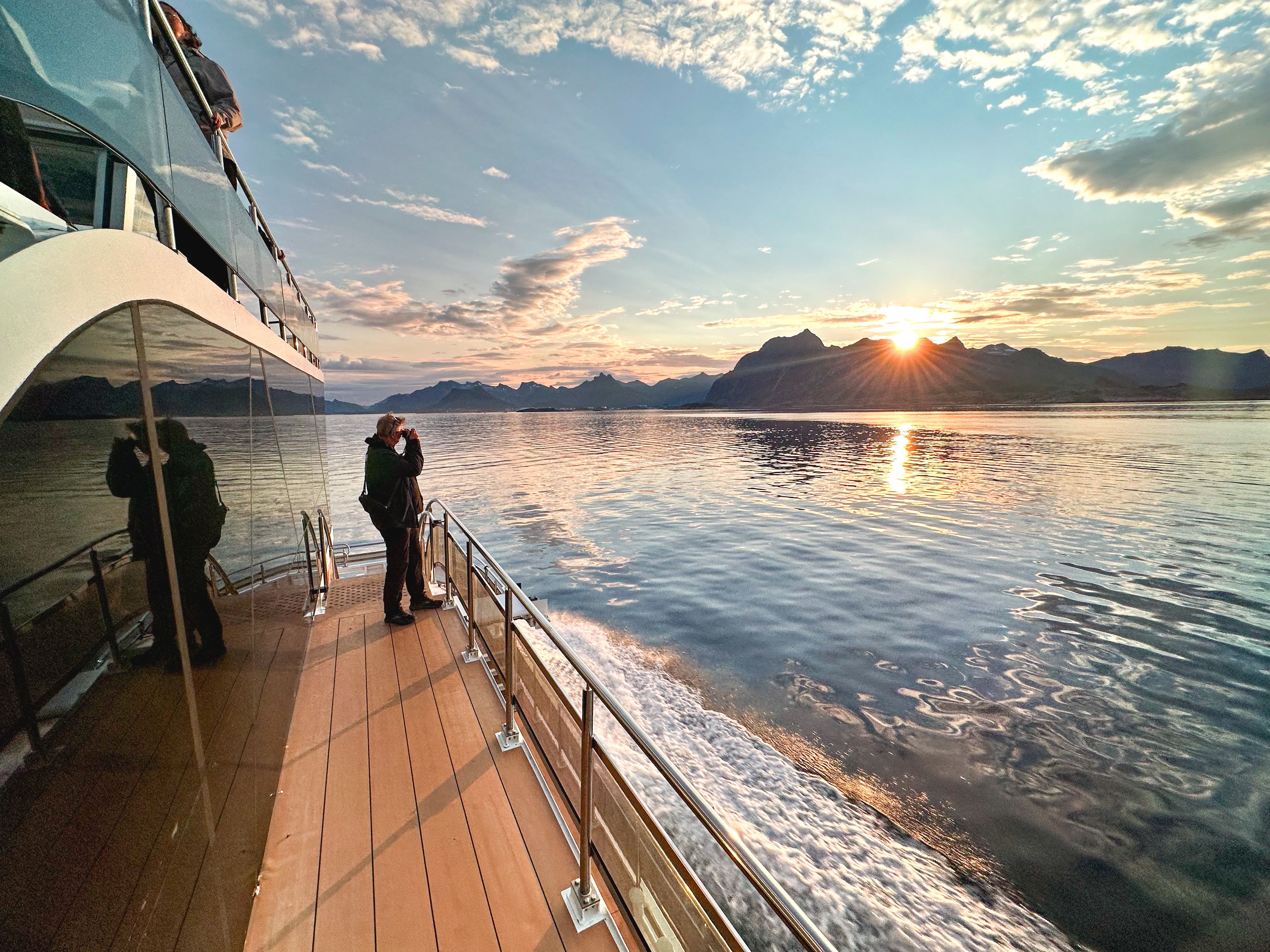 A person taking pictures of mountains from a boat.