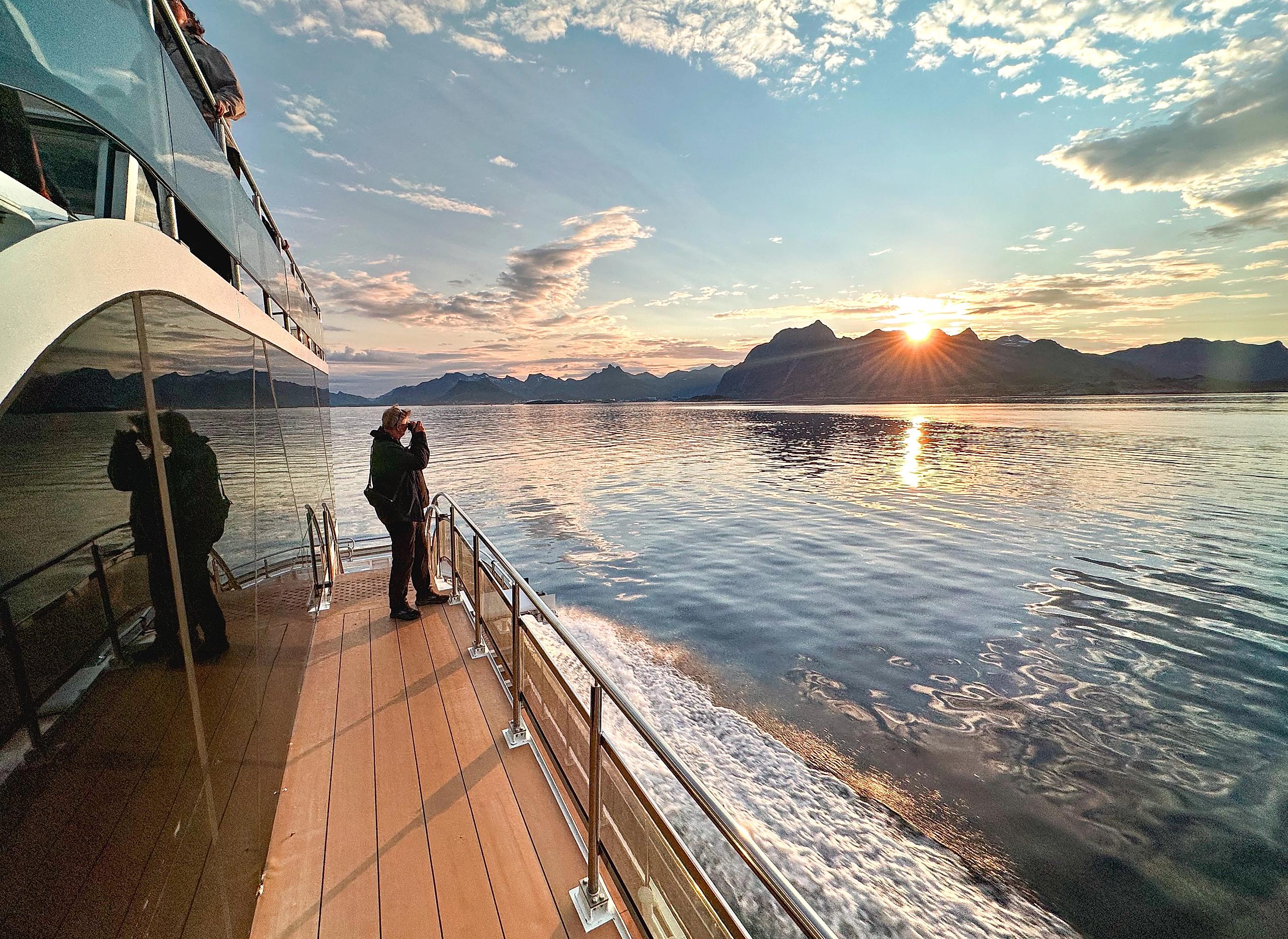 A person taking pictures of mountains from a boat.