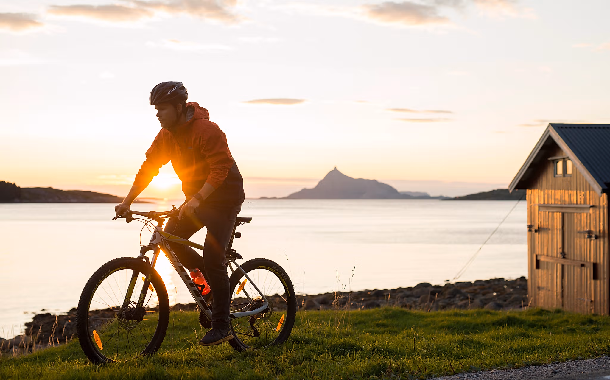 A person cycling in midnight sun on the Lurøy island in Helgeland, Northern Norway