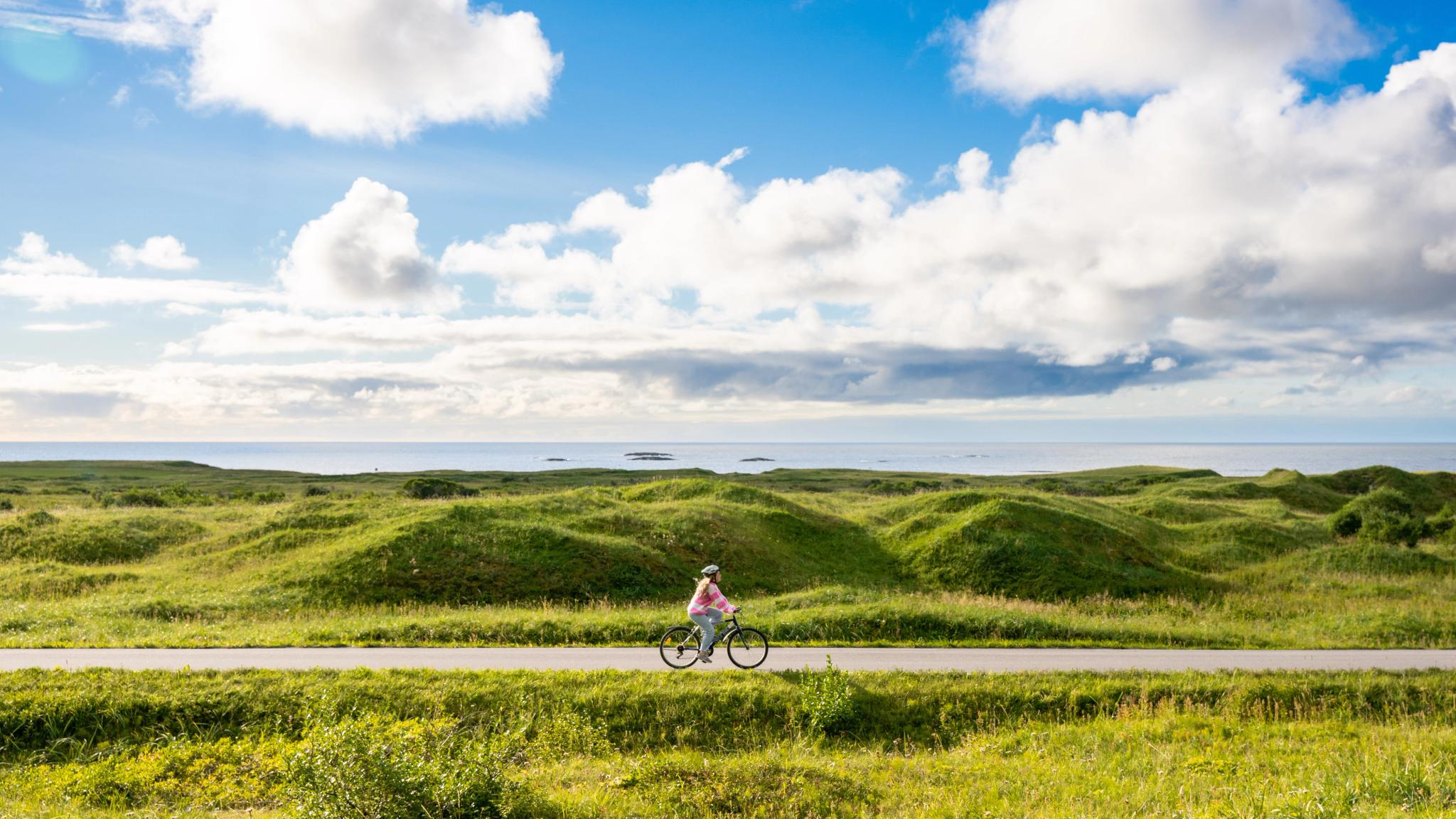 En kvinne sykler på Nasjonal turistveg Andøya