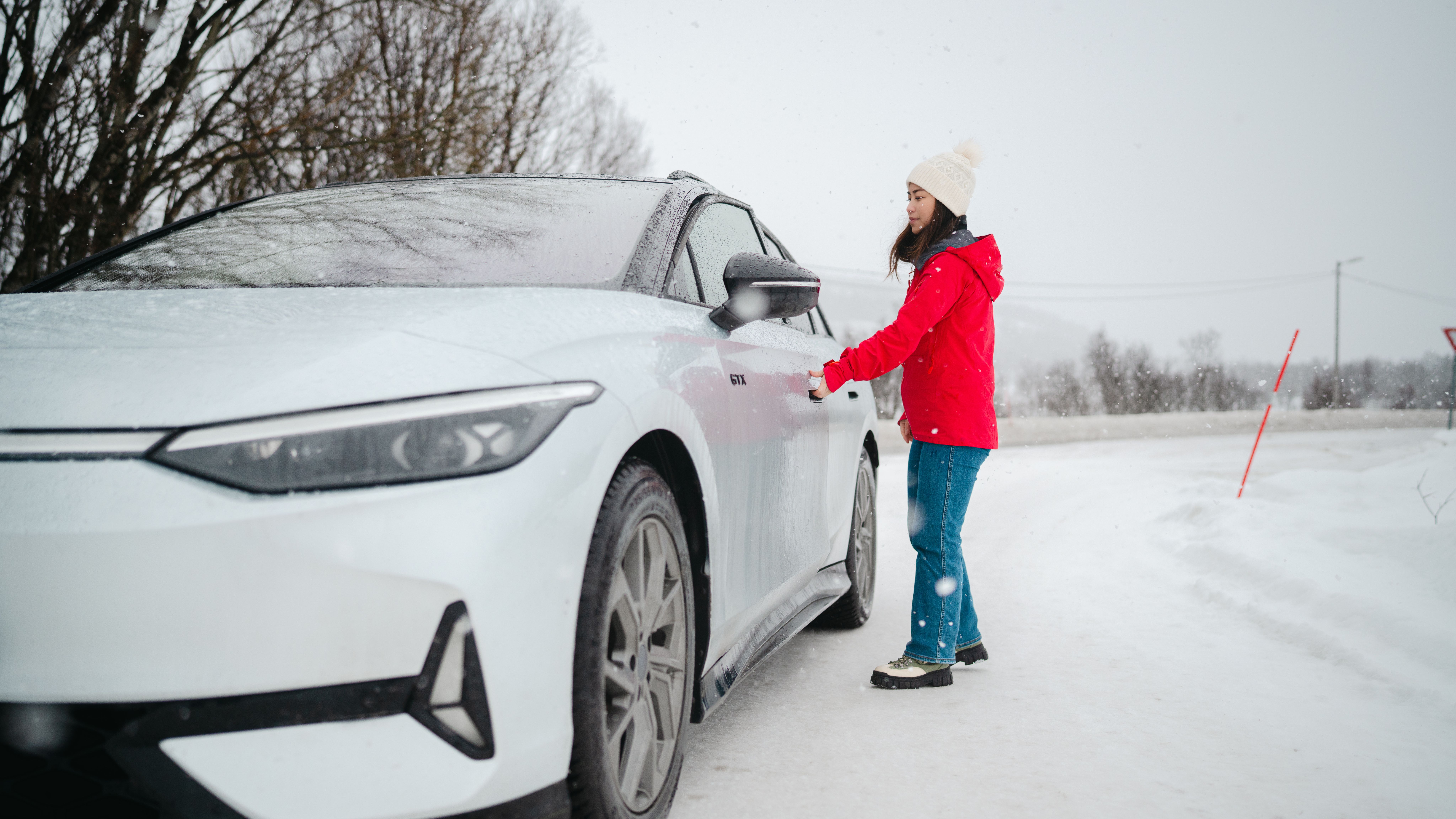 A woman opening a car door in winter landscape.