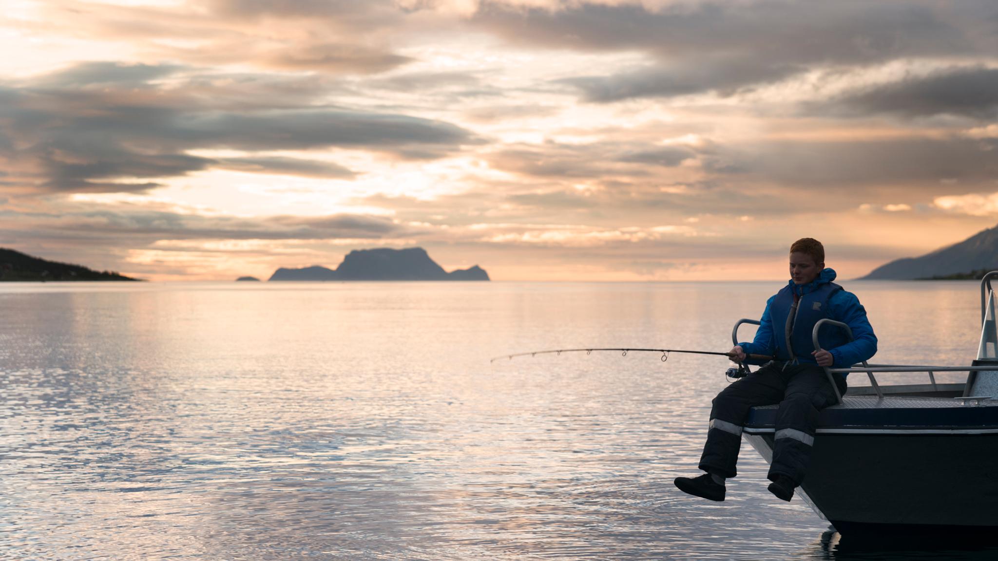 A person fishing under the midnight sun in Lyngen, Northern Norway