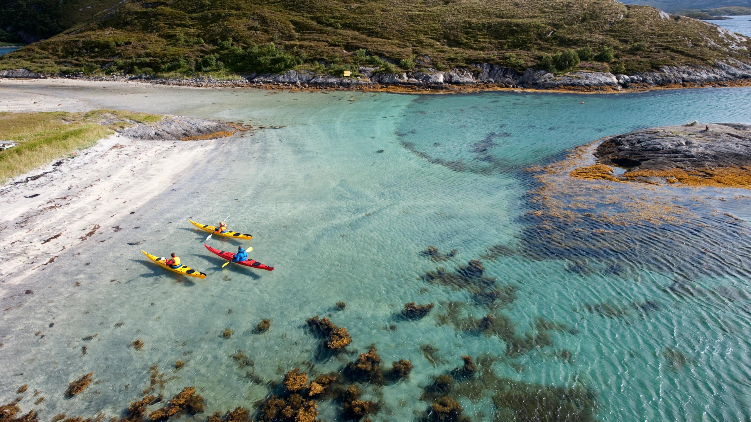Tre padlere i kajakk på en strand på Rødøy på Helgelandskysten i Nord-Norge