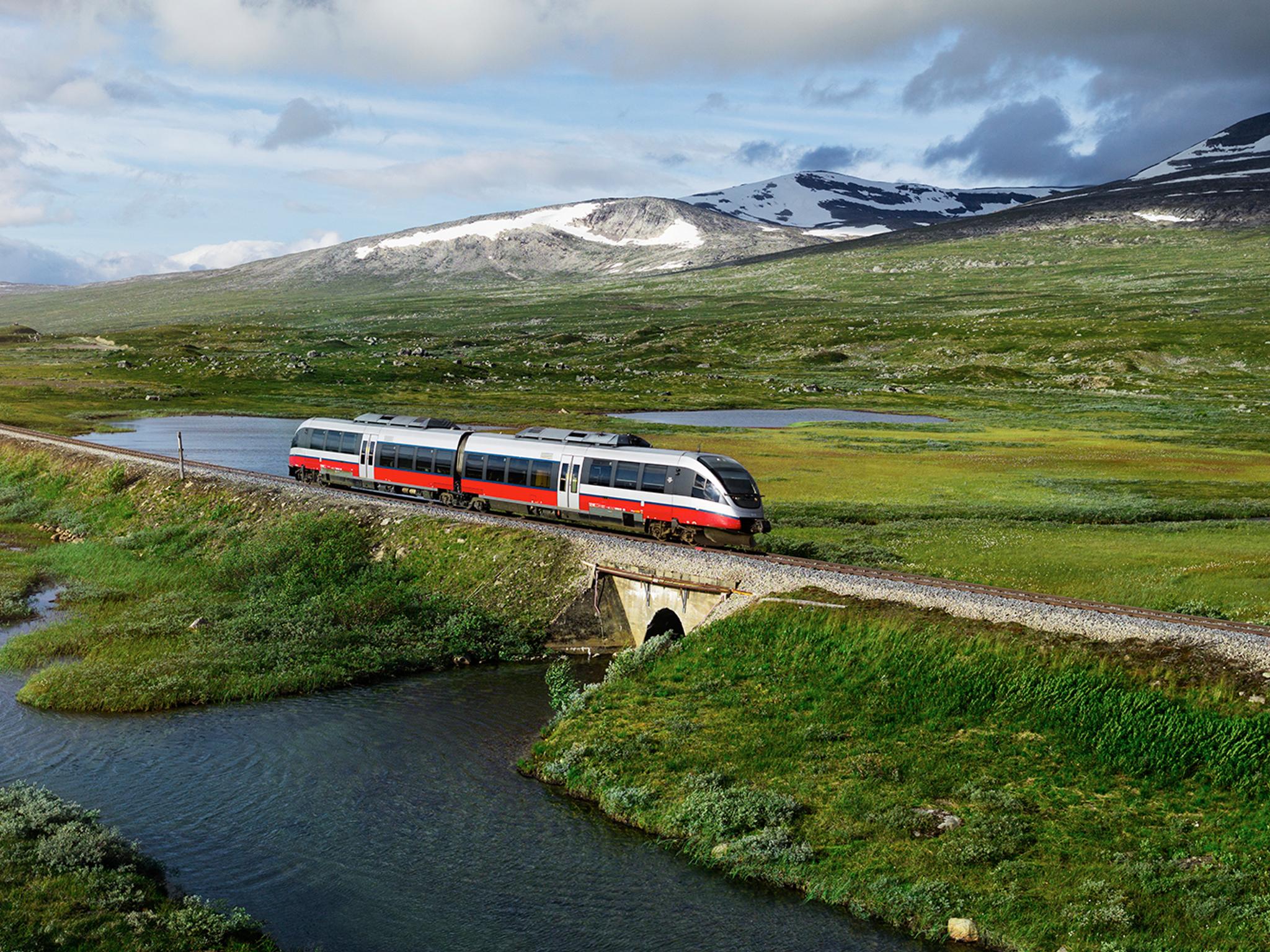 Et tog passerer en innsjø på Saltfjellet i Nordland