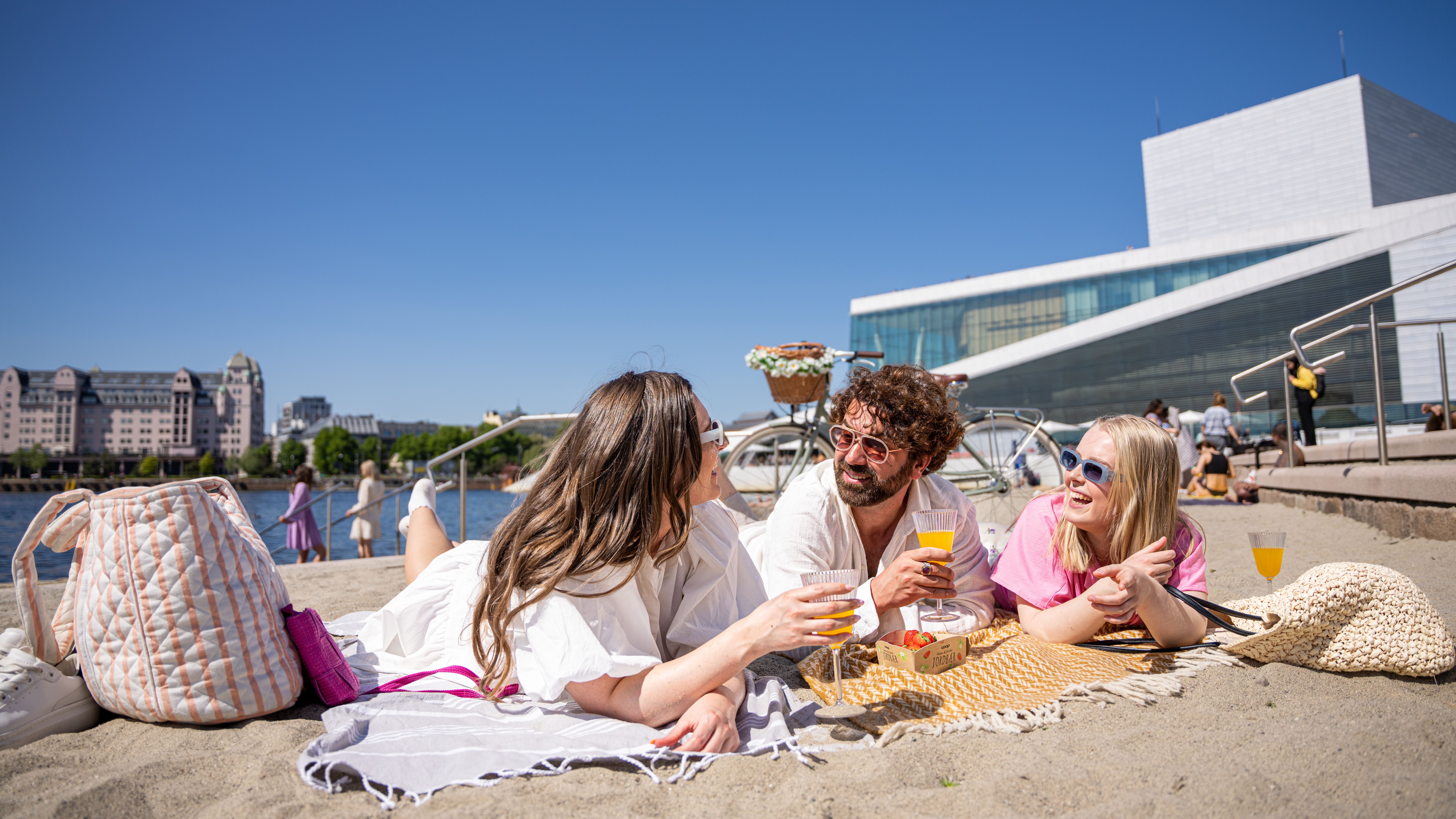 Three friends laying at the Operastranden beach in Oslo