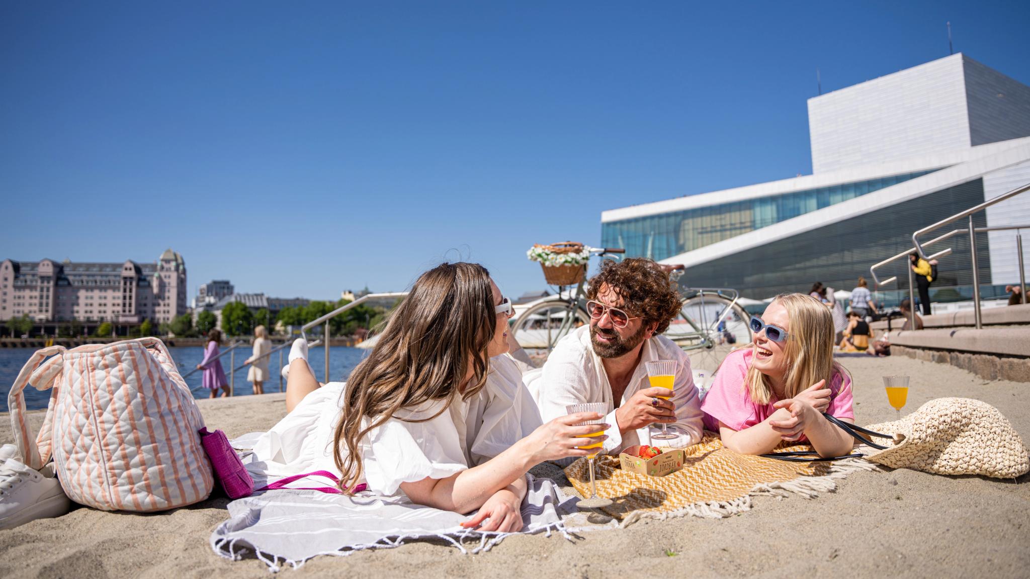 Three friends laying at the Operastranden beach in Oslo