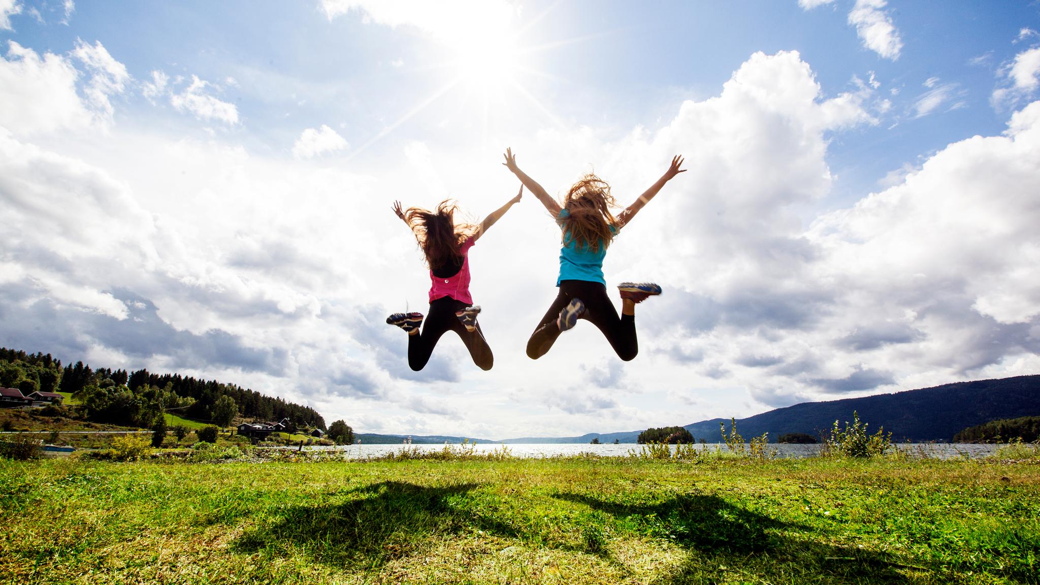 Two girls jumping in the air by Randsfjorden