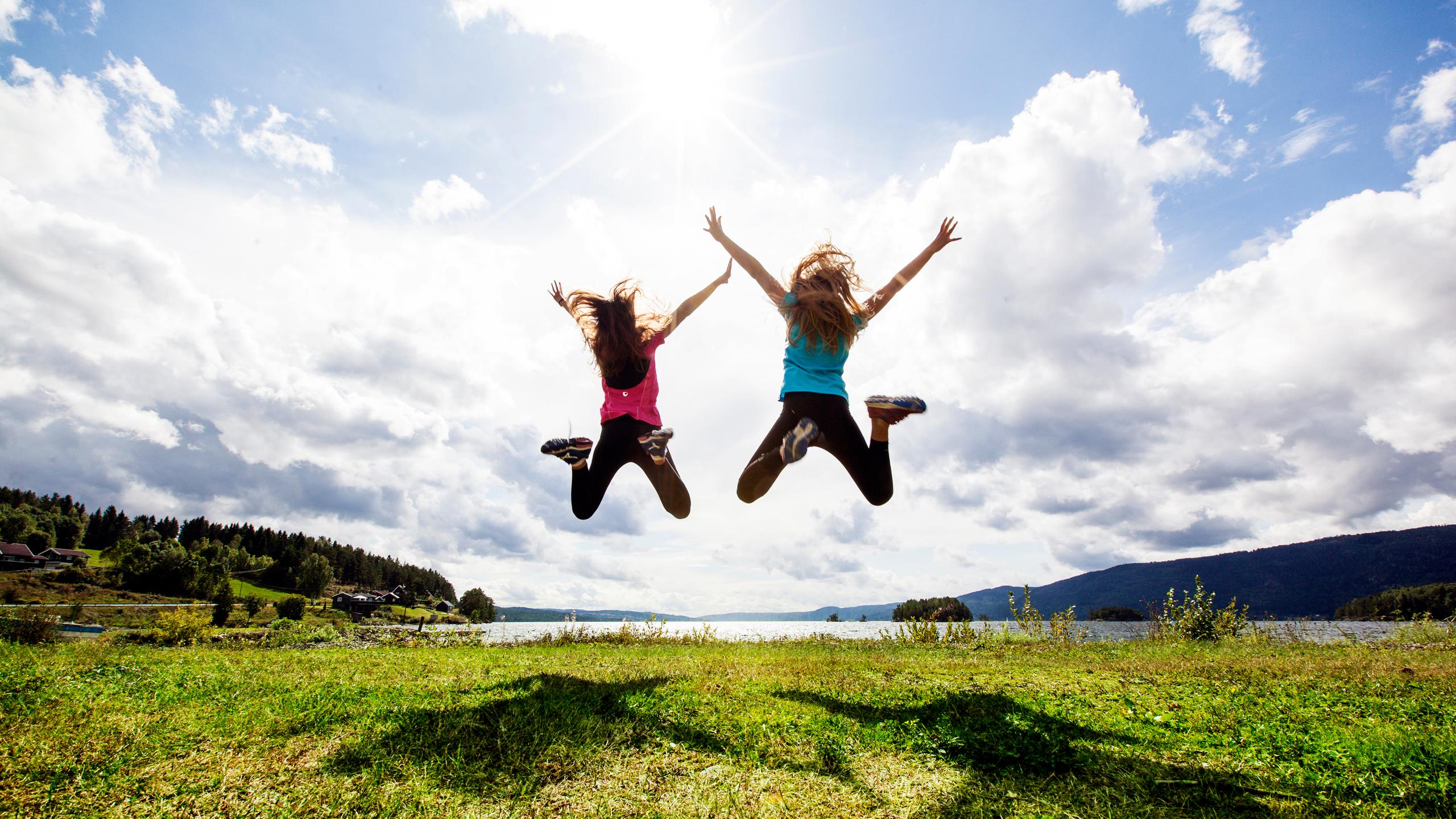Two girls jumping in the air by Randsfjorden
