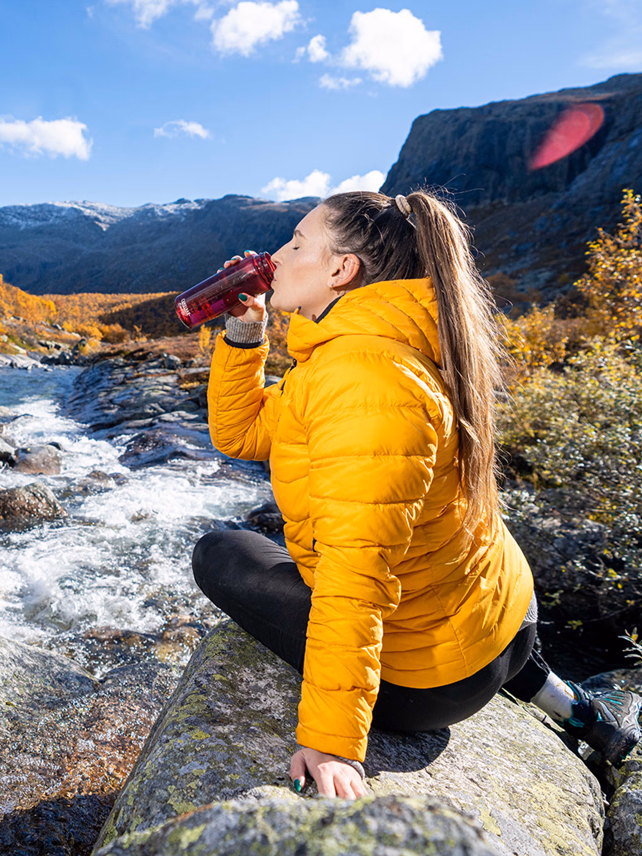 Woman drinking water from a river, Hemsedal, Norway.