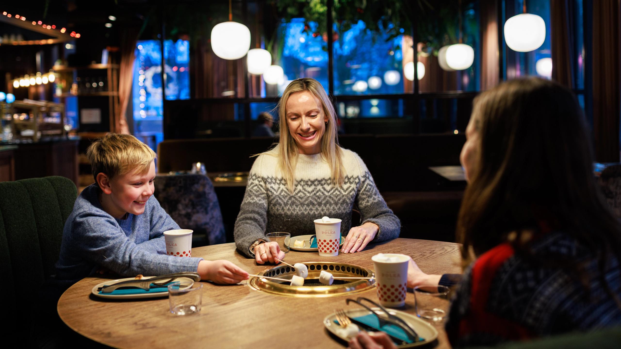 Two women and a boy grilling marshmellows at the restaurant POLKA Grill & Spiseri in Stavanger
