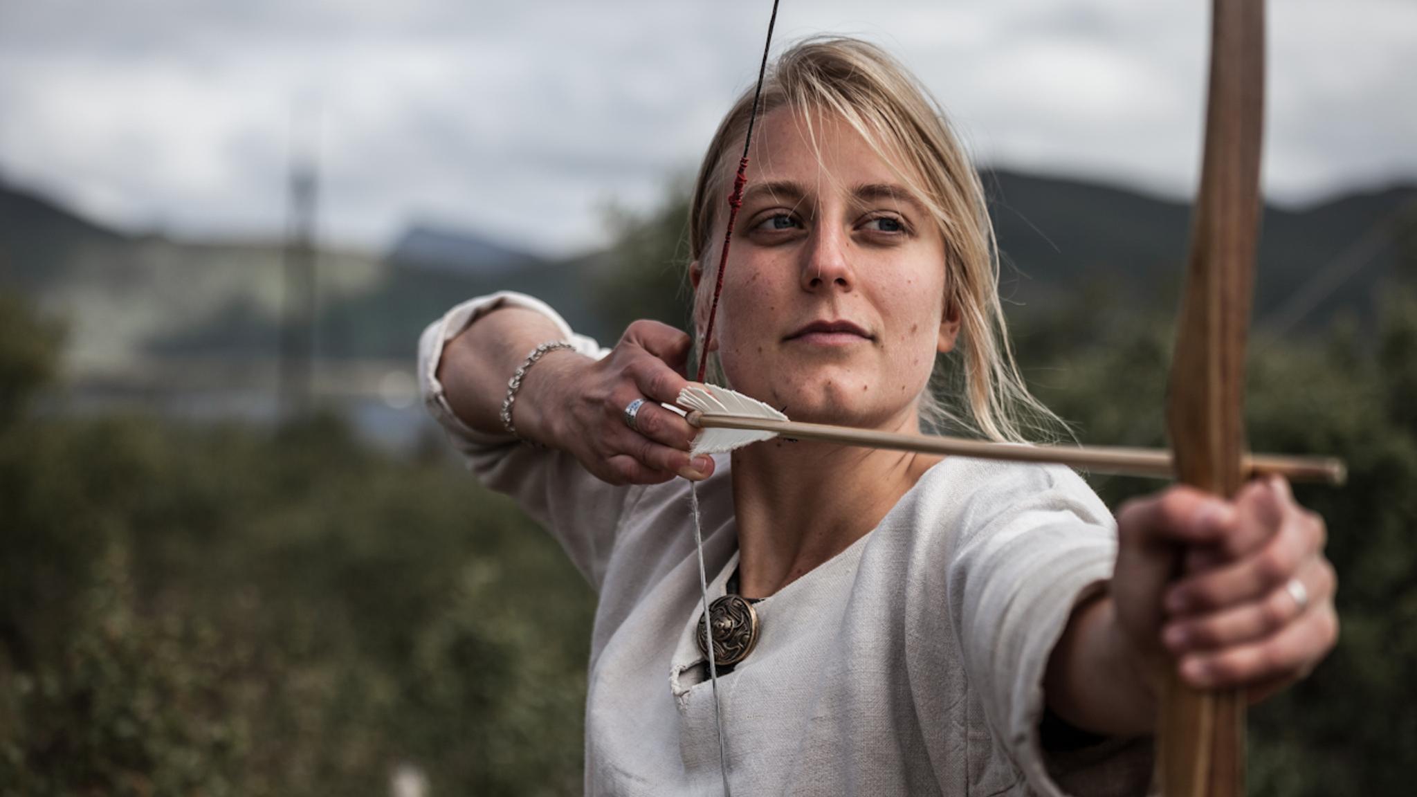 Woman shooting with a bow and arrow at the Lofotr Viking Museum