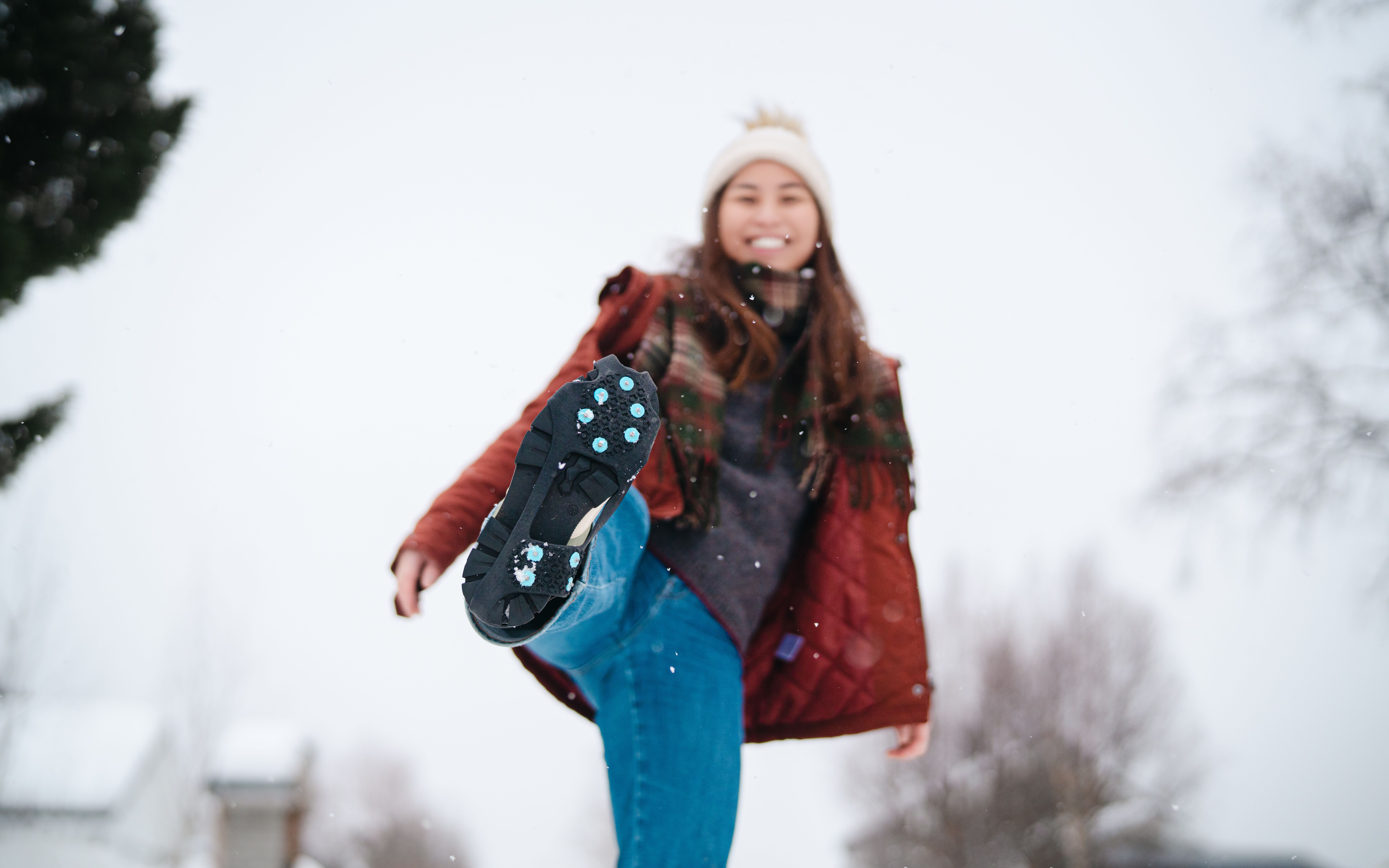 A woman showes her ice cleats to the camera.