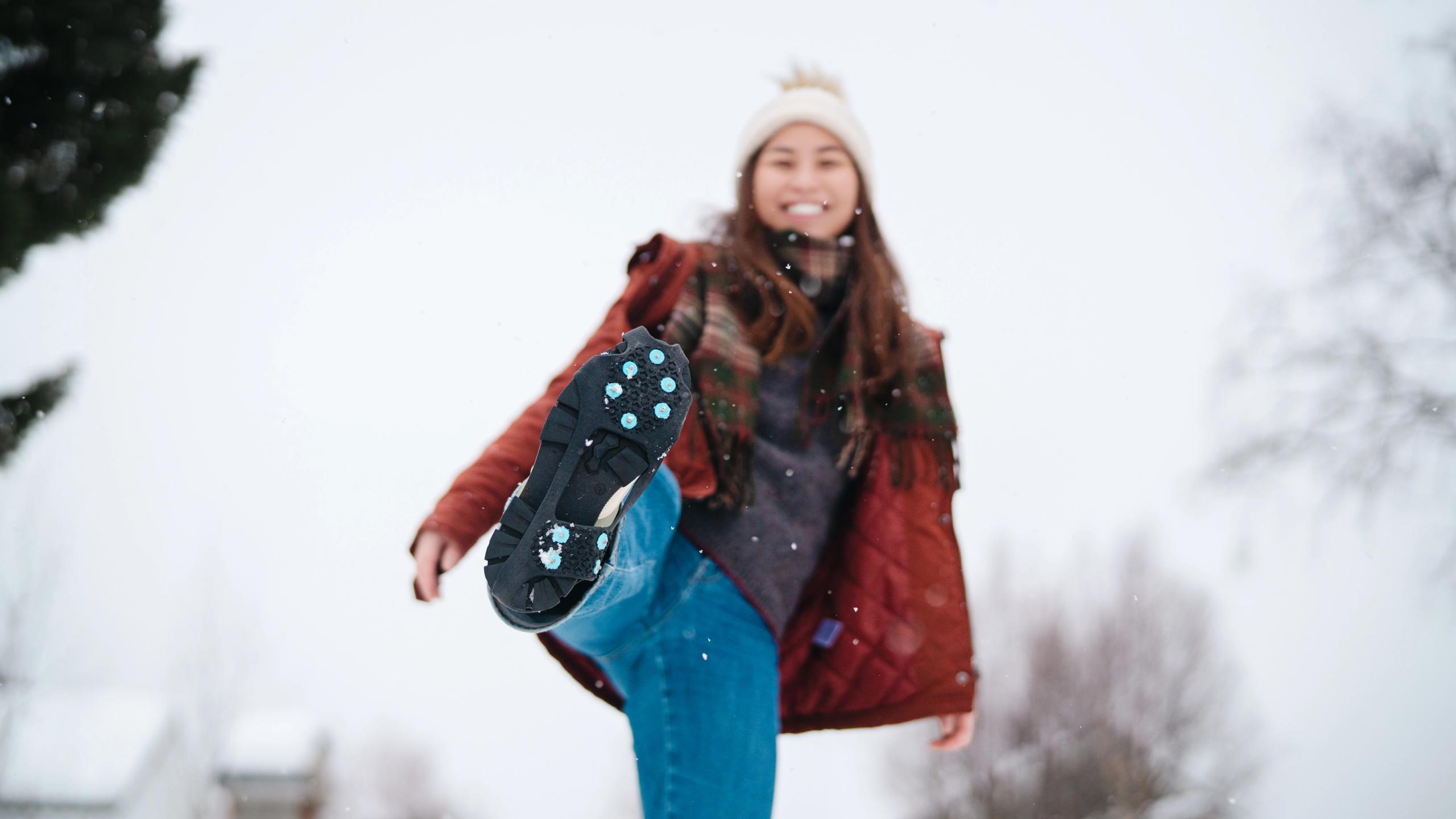 A woman showes her ice cleats to the camera.