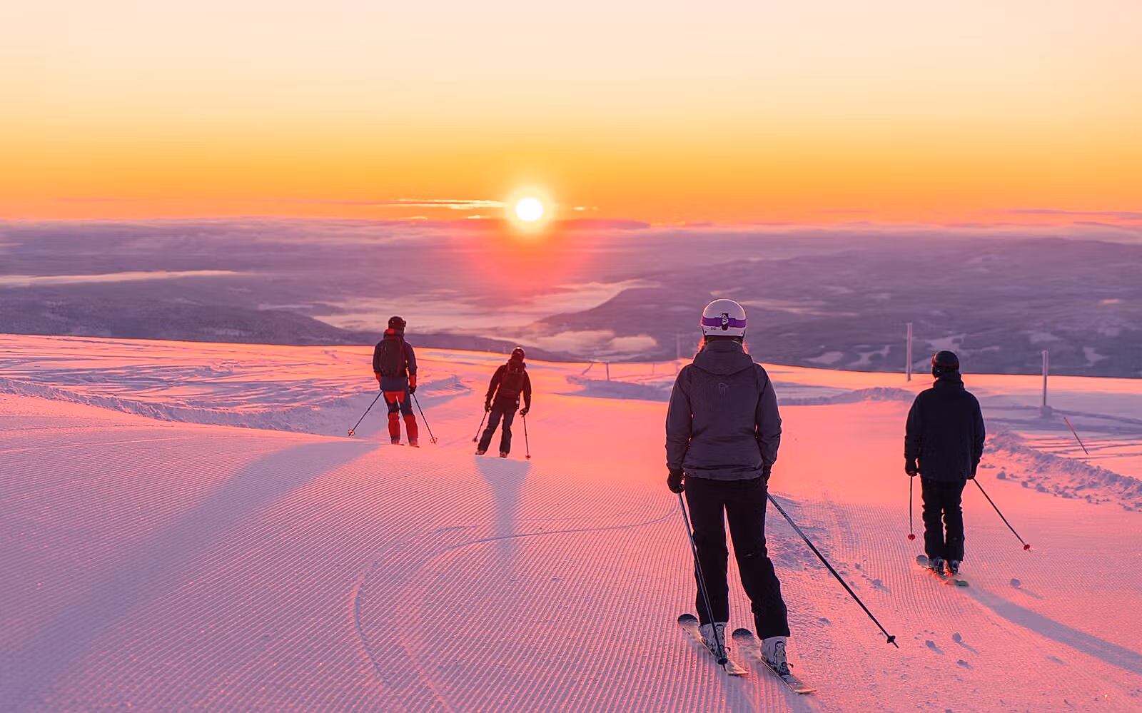 Four people skiing downhill in sunrise at Norefjell ski resort, Eastern Norway