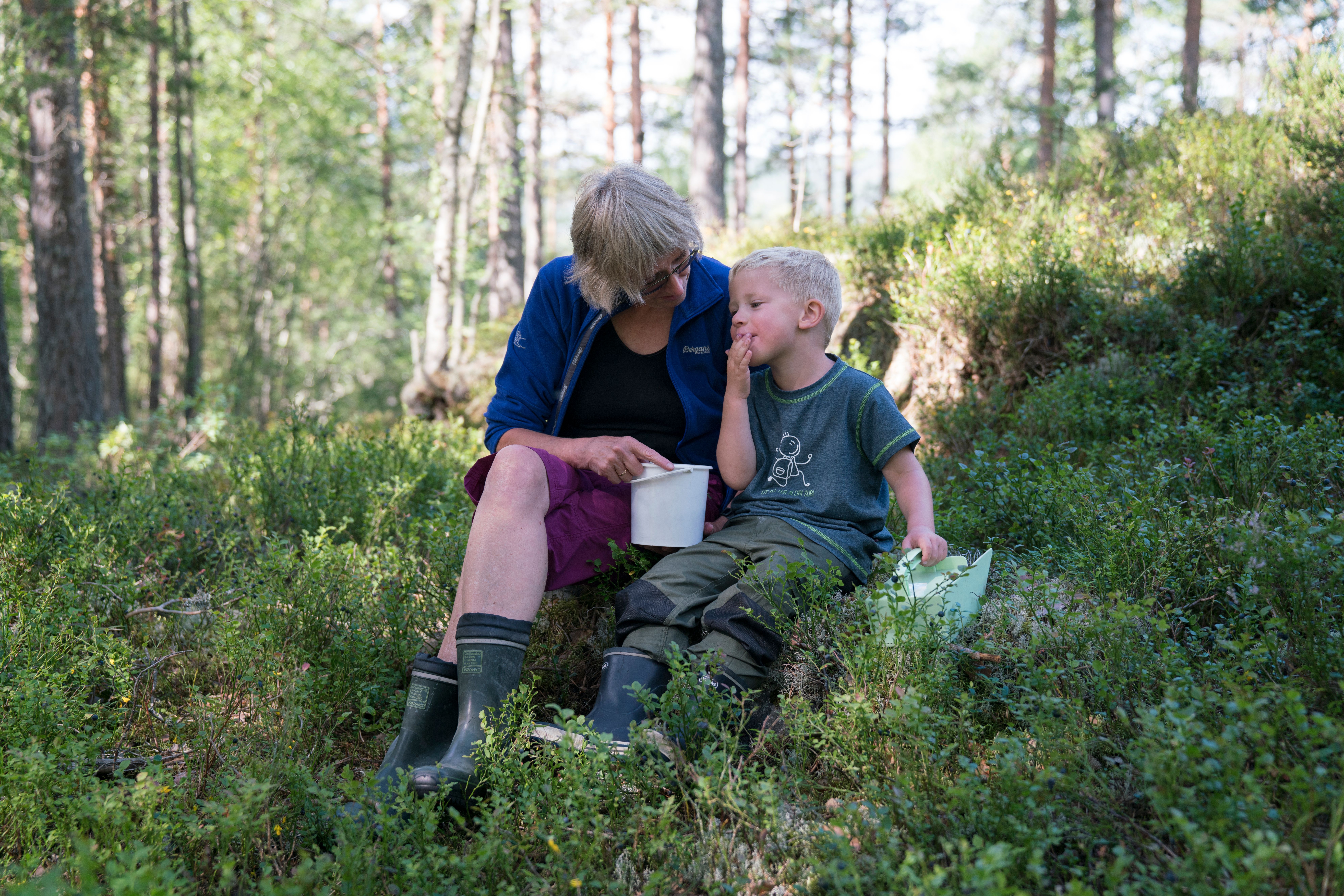A boy and his grandmother enjoying blueberries in the forest outside Kongsberg in Eastern Norway