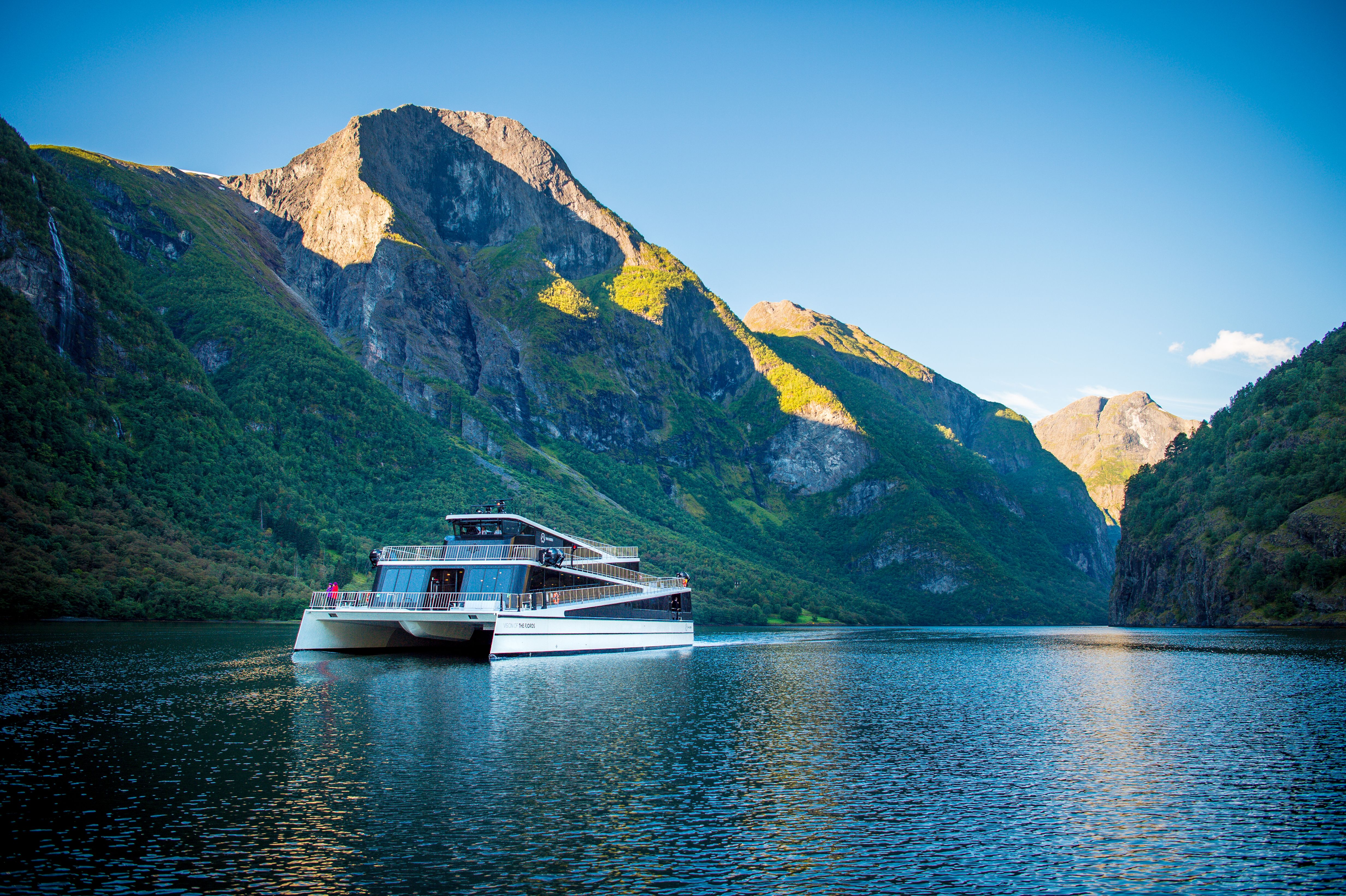 The ship Vision of the Fjords sailing between high mountains on a sunny summer day in Fjord Norway