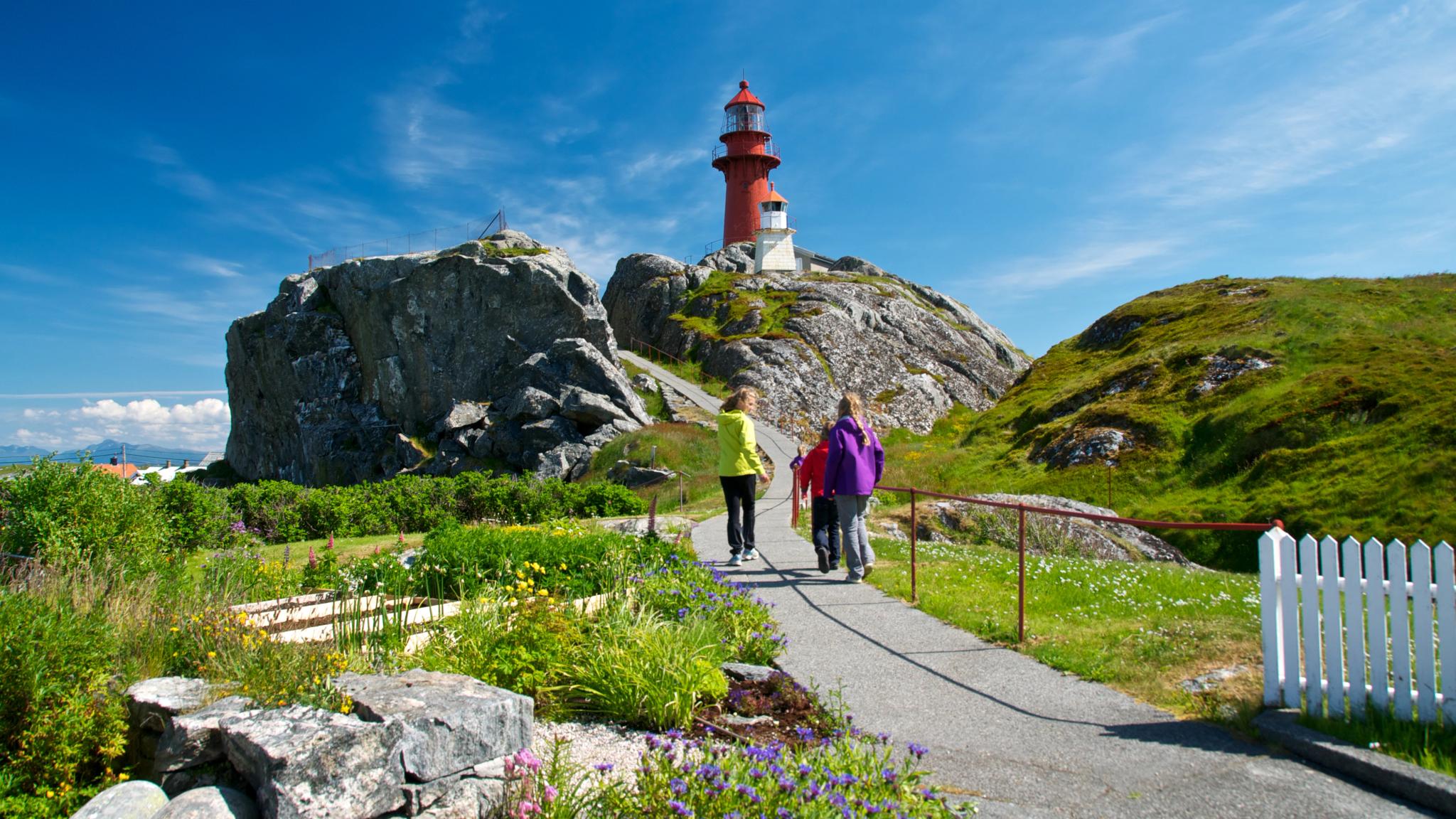 Personer går tur ved Ona fyr i havgapet nord for Ålesund, Norge.