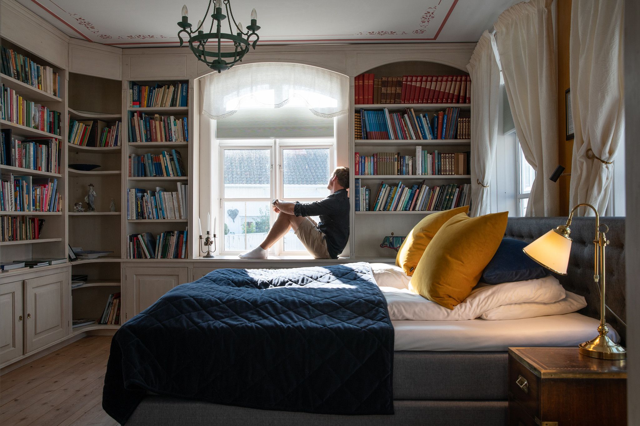 Een persoon op een bed in Det Lille Hotel in Risør, Zuid-Noorwegen
