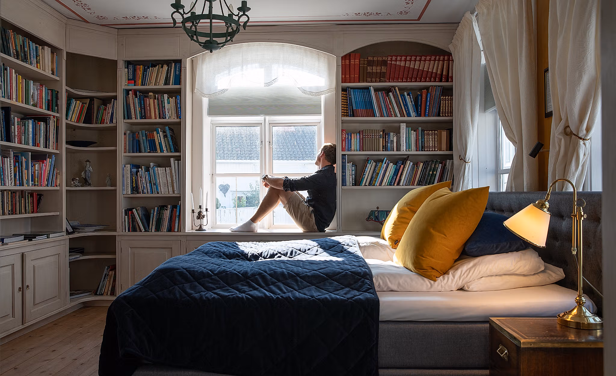 Een persoon op een bed in Det Lille Hotel in Risør, Zuid-Noorwegen