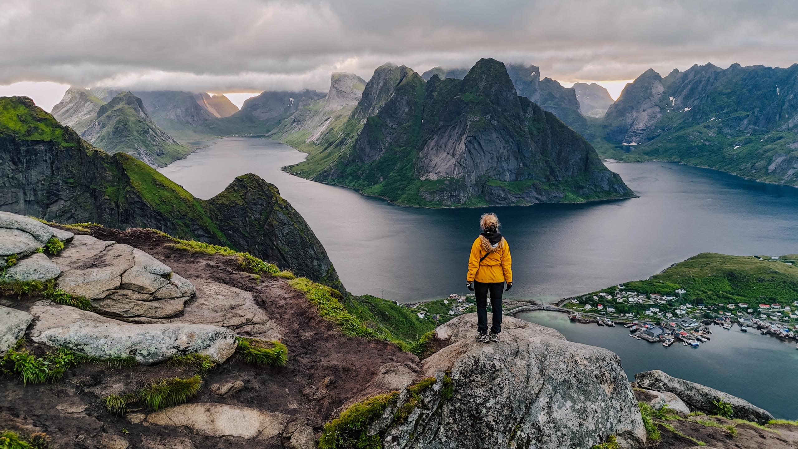 En person står på toppen av Reinebringen i Lofoten.