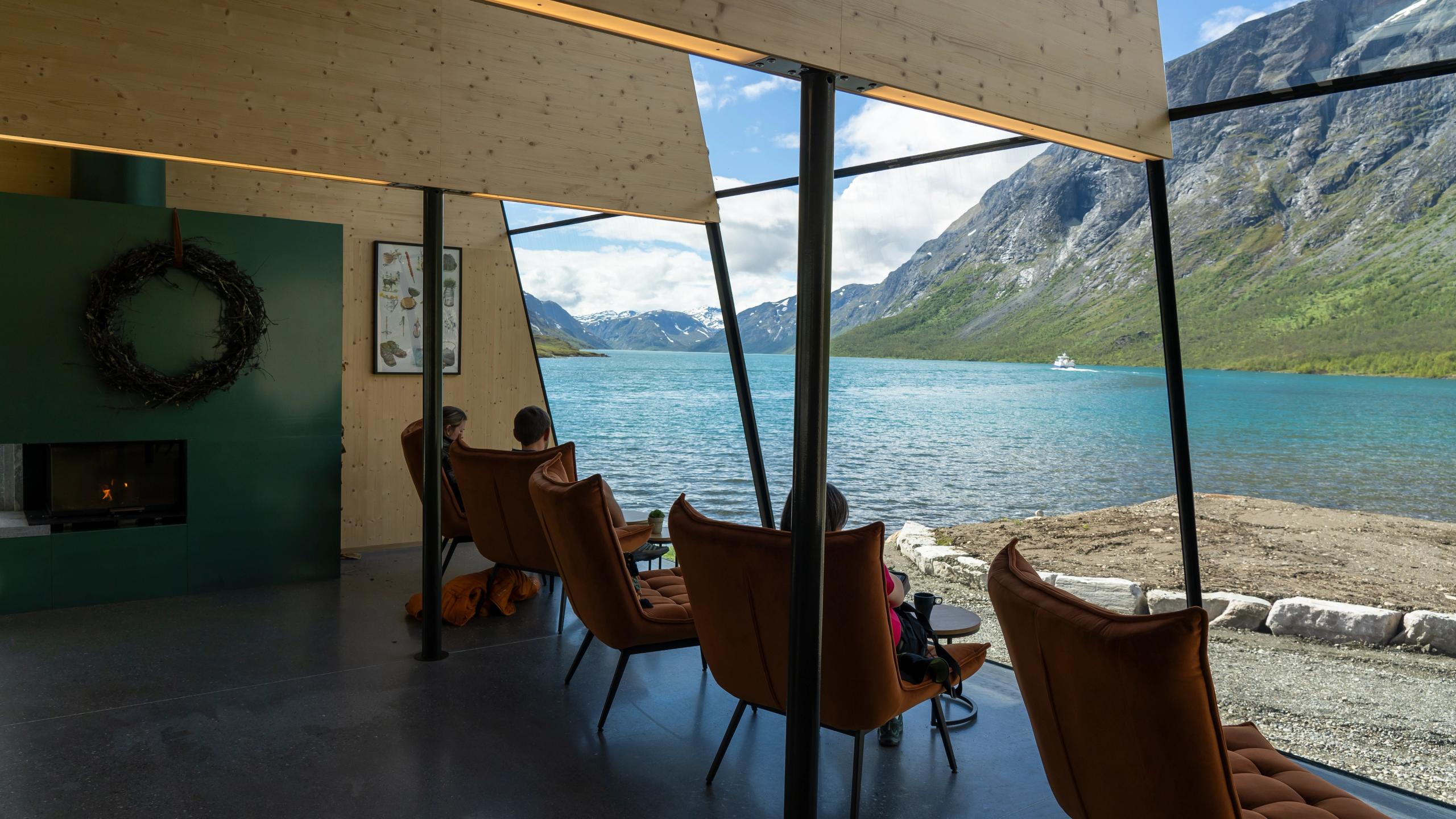 People sitting inside of Café Gjendeosen with view out to the Gjende lake.