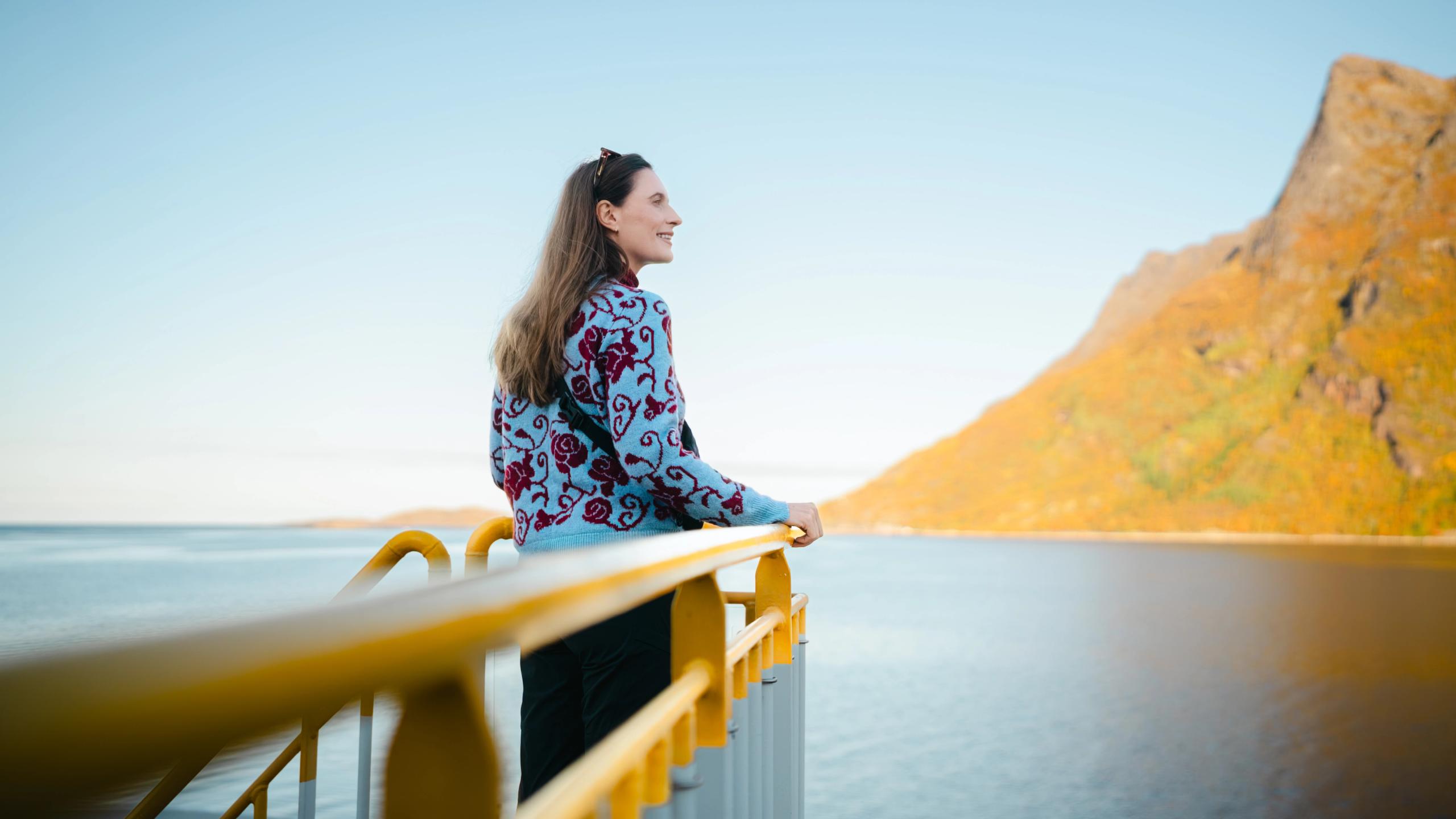 En kvinne står på dekk og ser ut over Kjerringøy, utenfor Bodø i Nord-Norge.