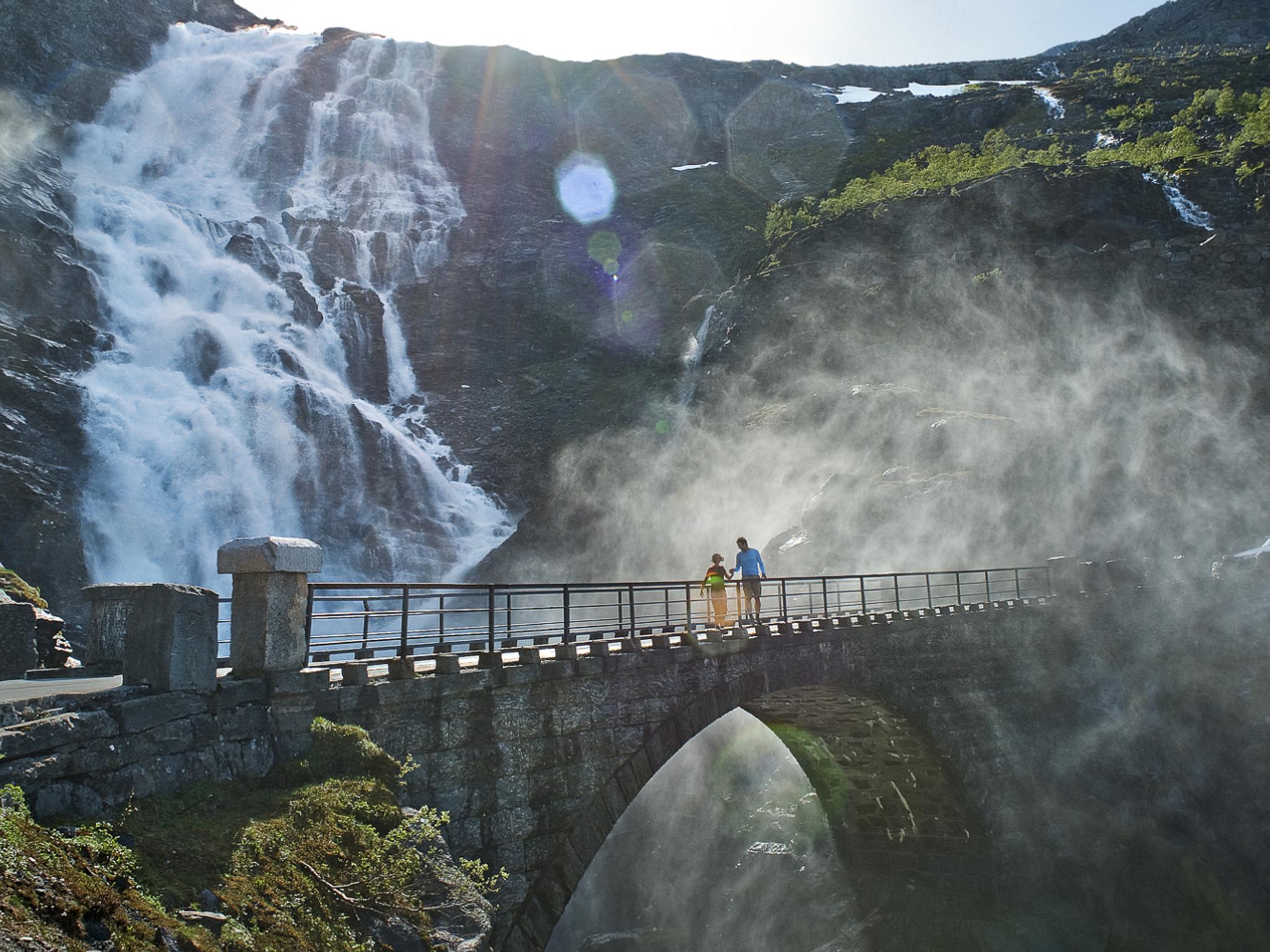 Two people running over a bridge at the Trollstigen road, in Rauma