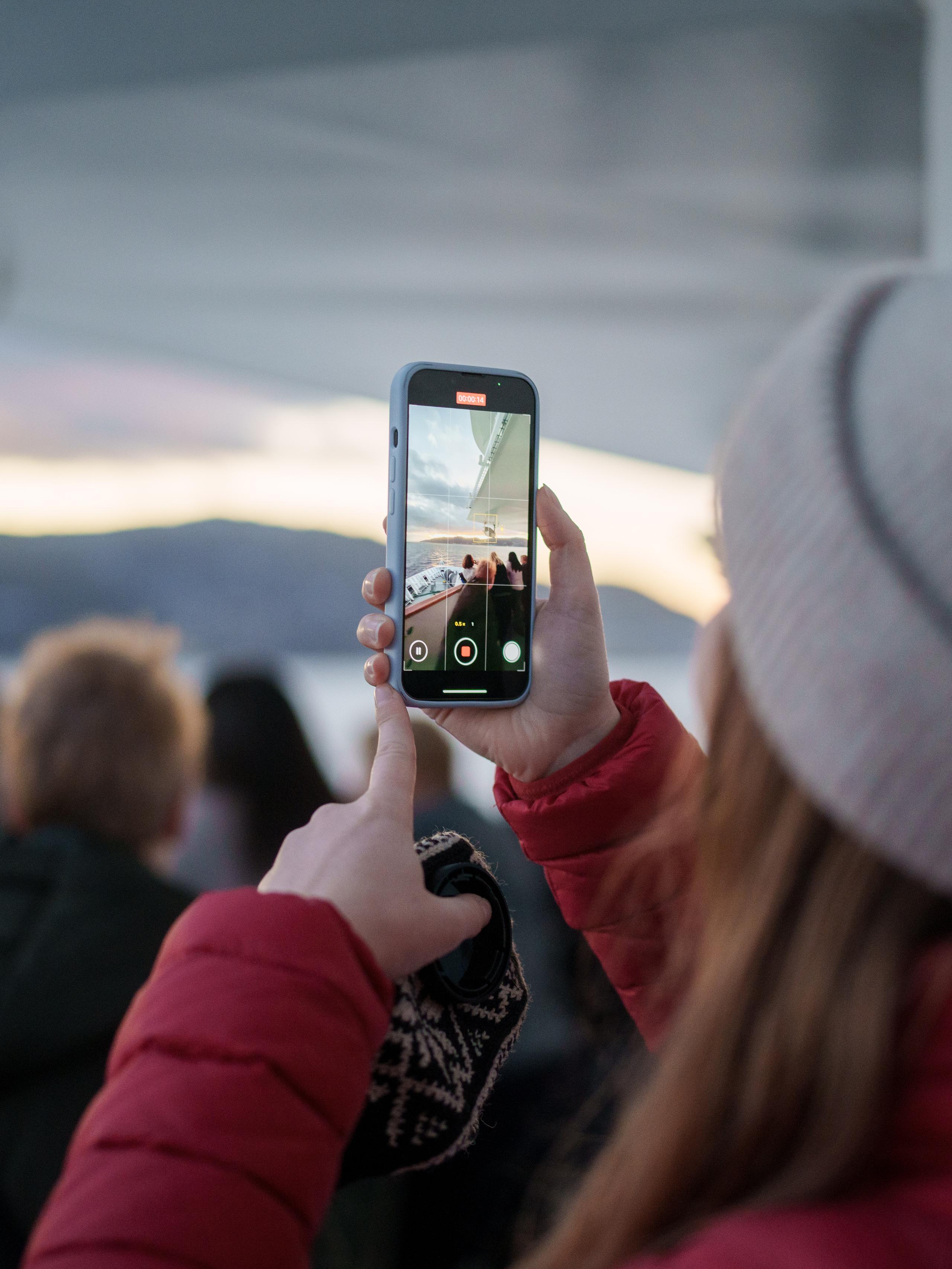 Woman filming a video on deck at Hurtigruten