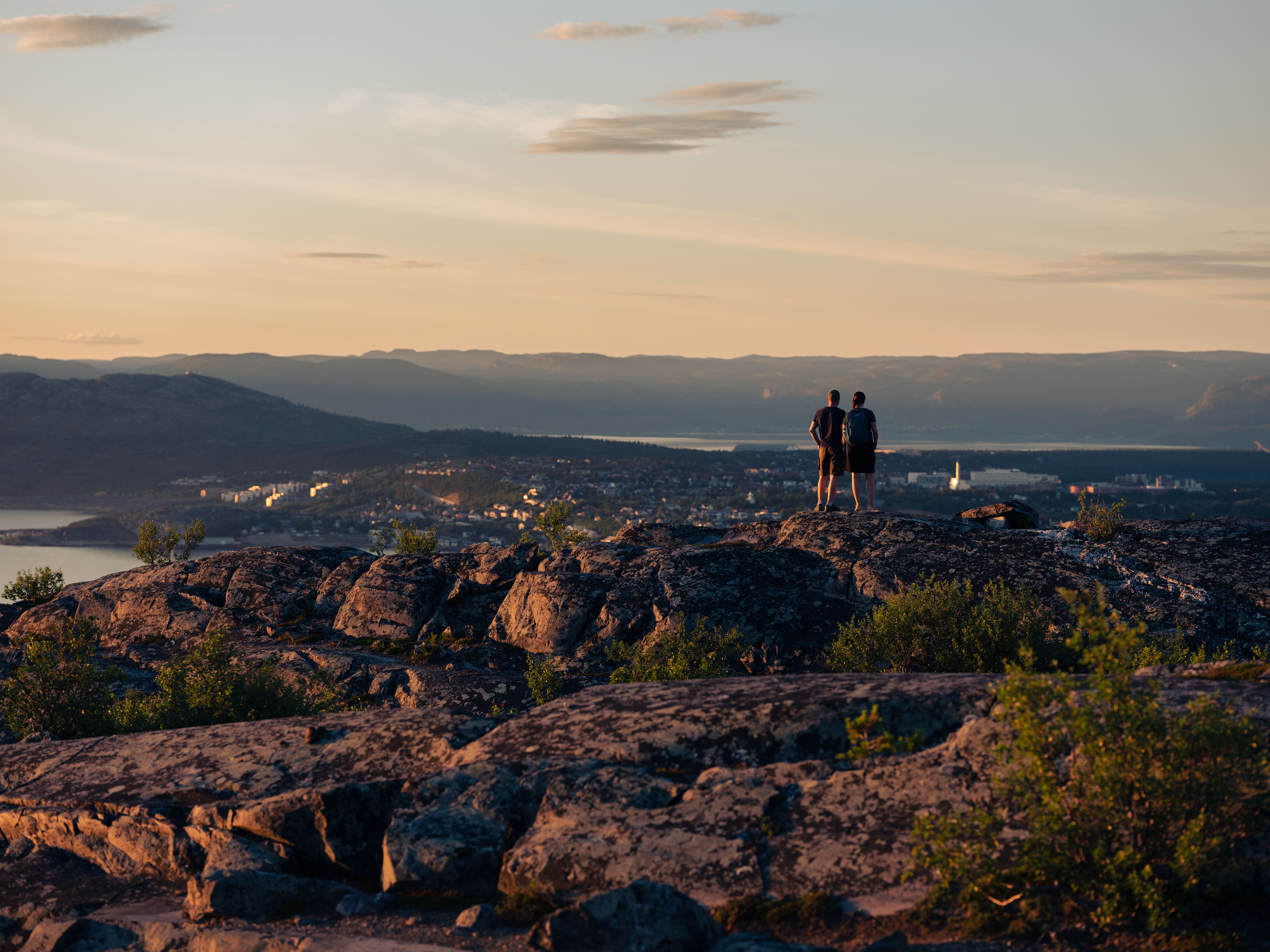 Two people looking at a town from a mountaintop.