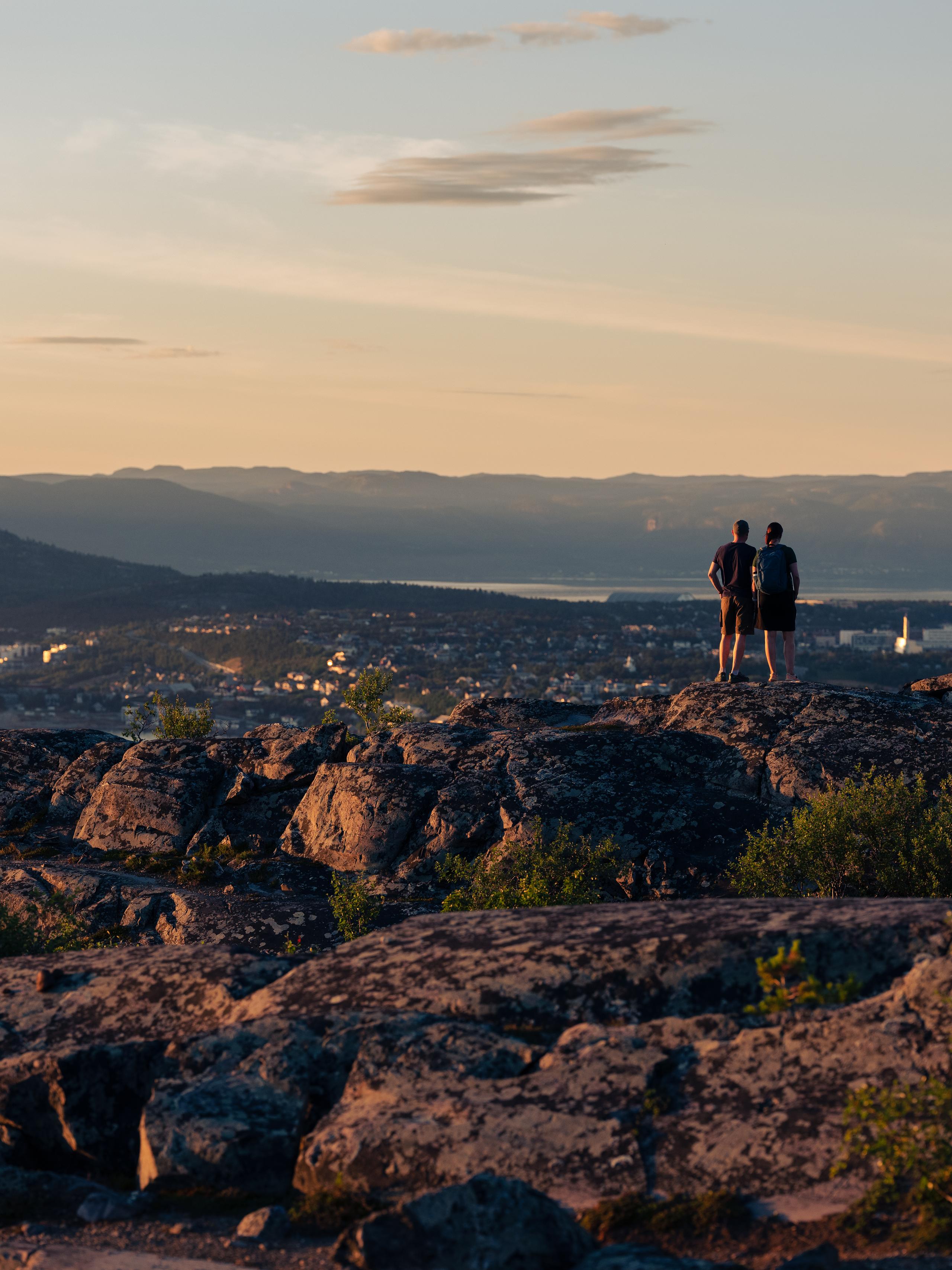 Two people looking at a town from a mountaintop.