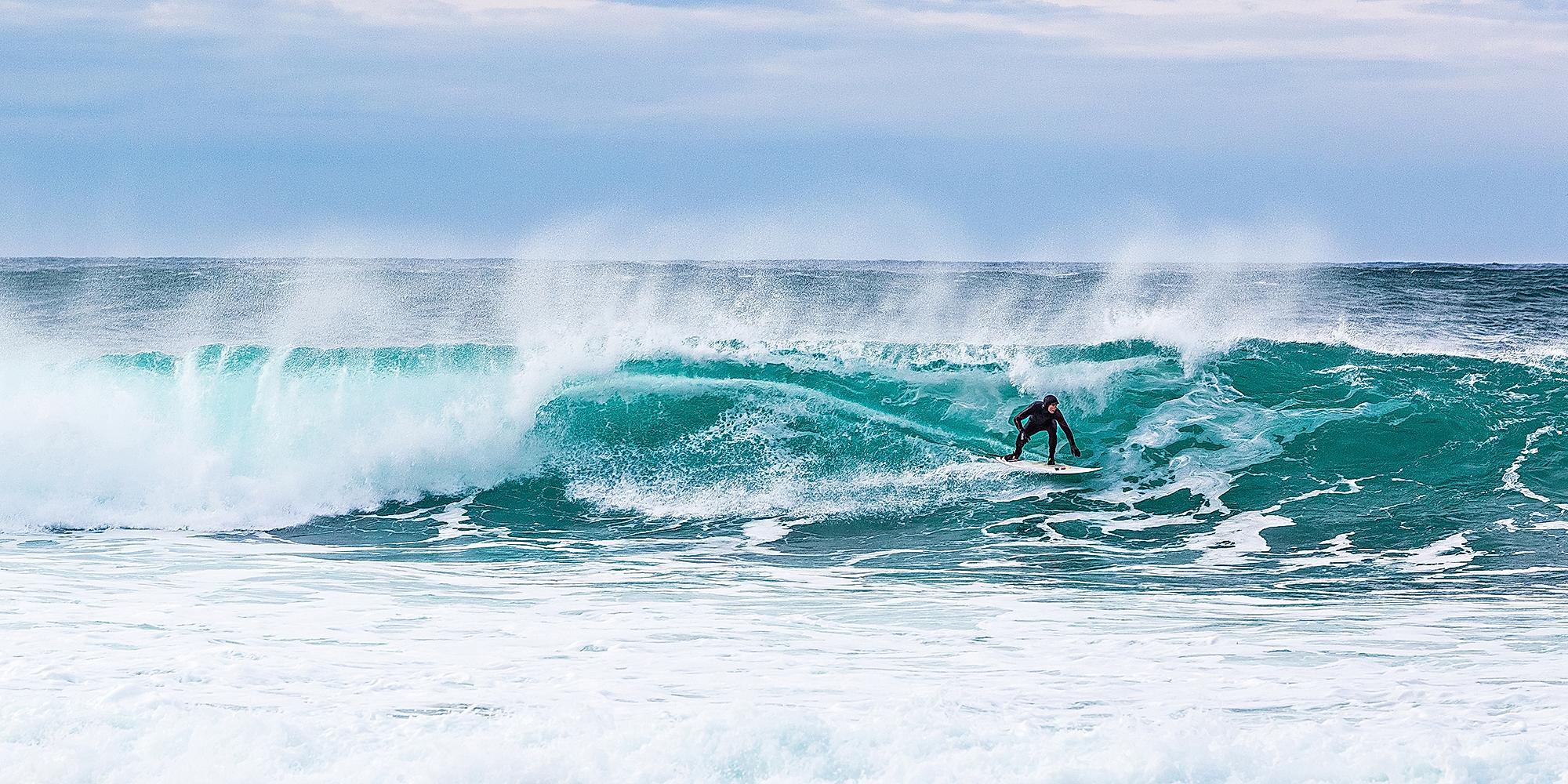 Surfer riding a breaking wave at Unstad in Lofoten, Northern Norway