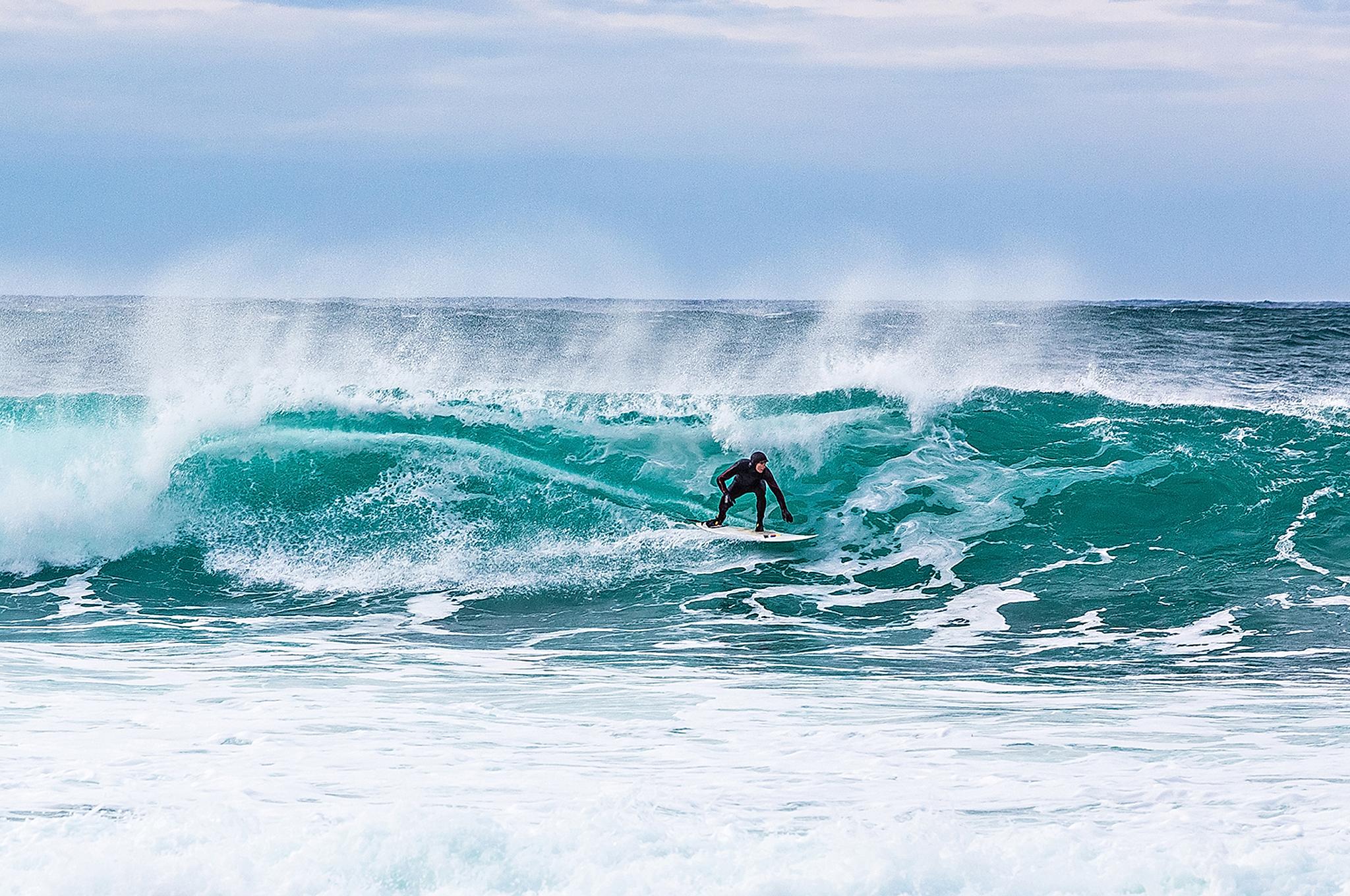 Surfer riding a breaking wave at Unstad in Lofoten, Northern Norway