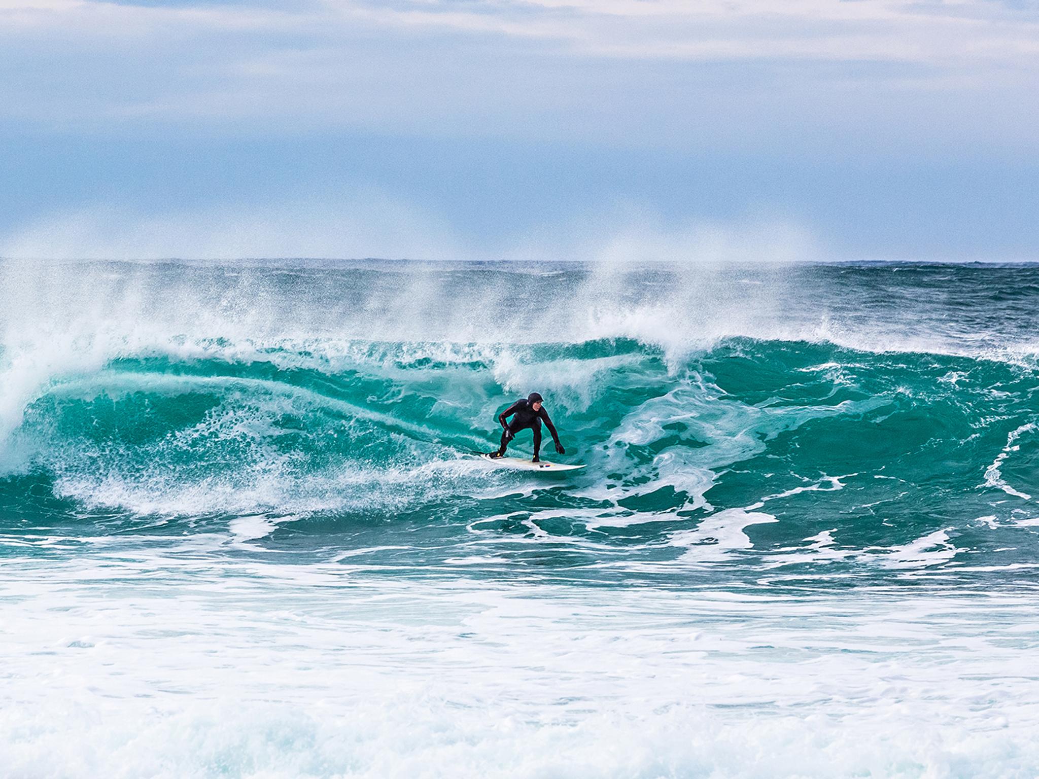 En mann surfer en bølge på Unstad i Lofoten