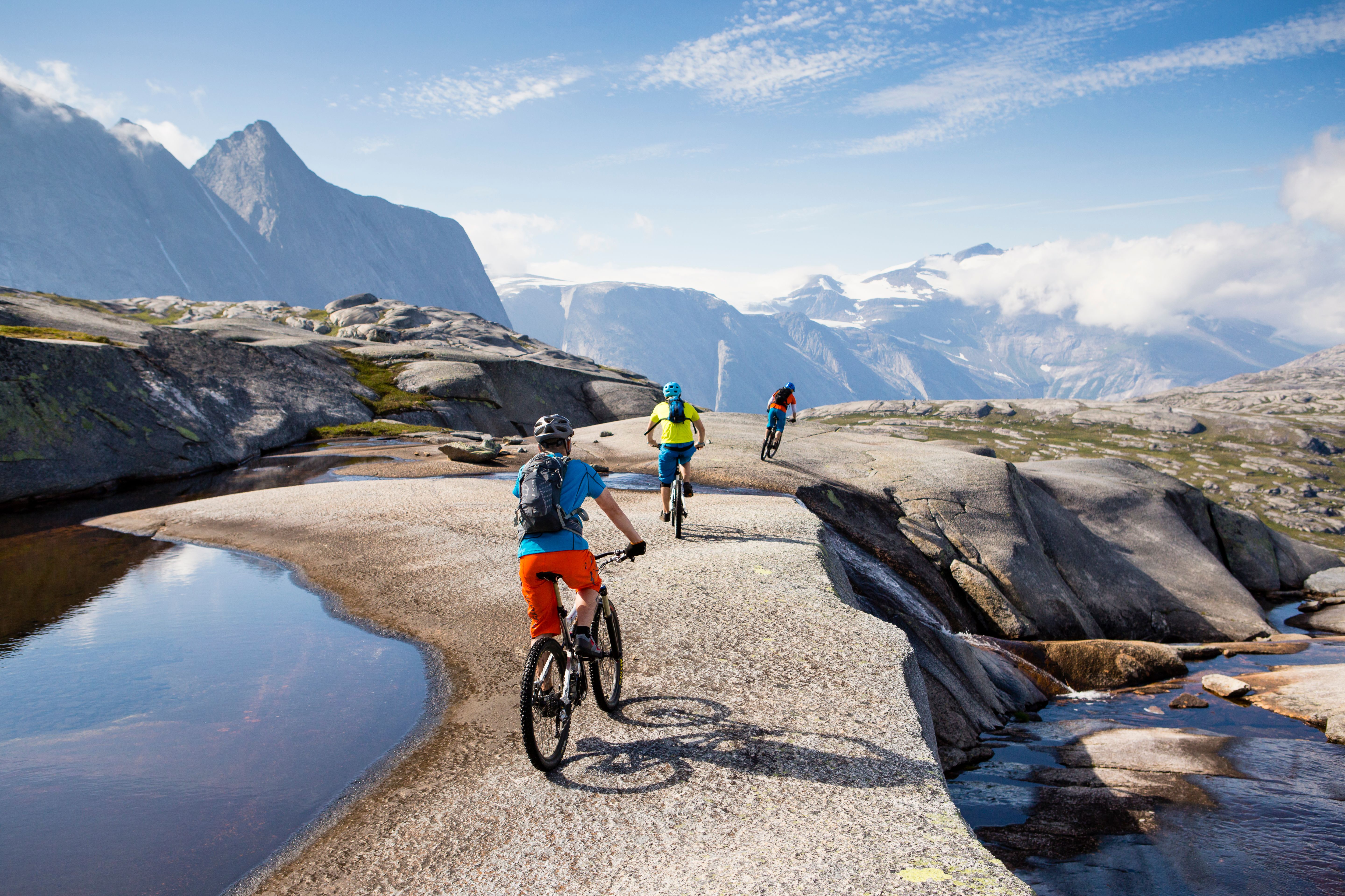 Three people mountain biking in Narvik in Northern Norway, surrounded by tall mountains